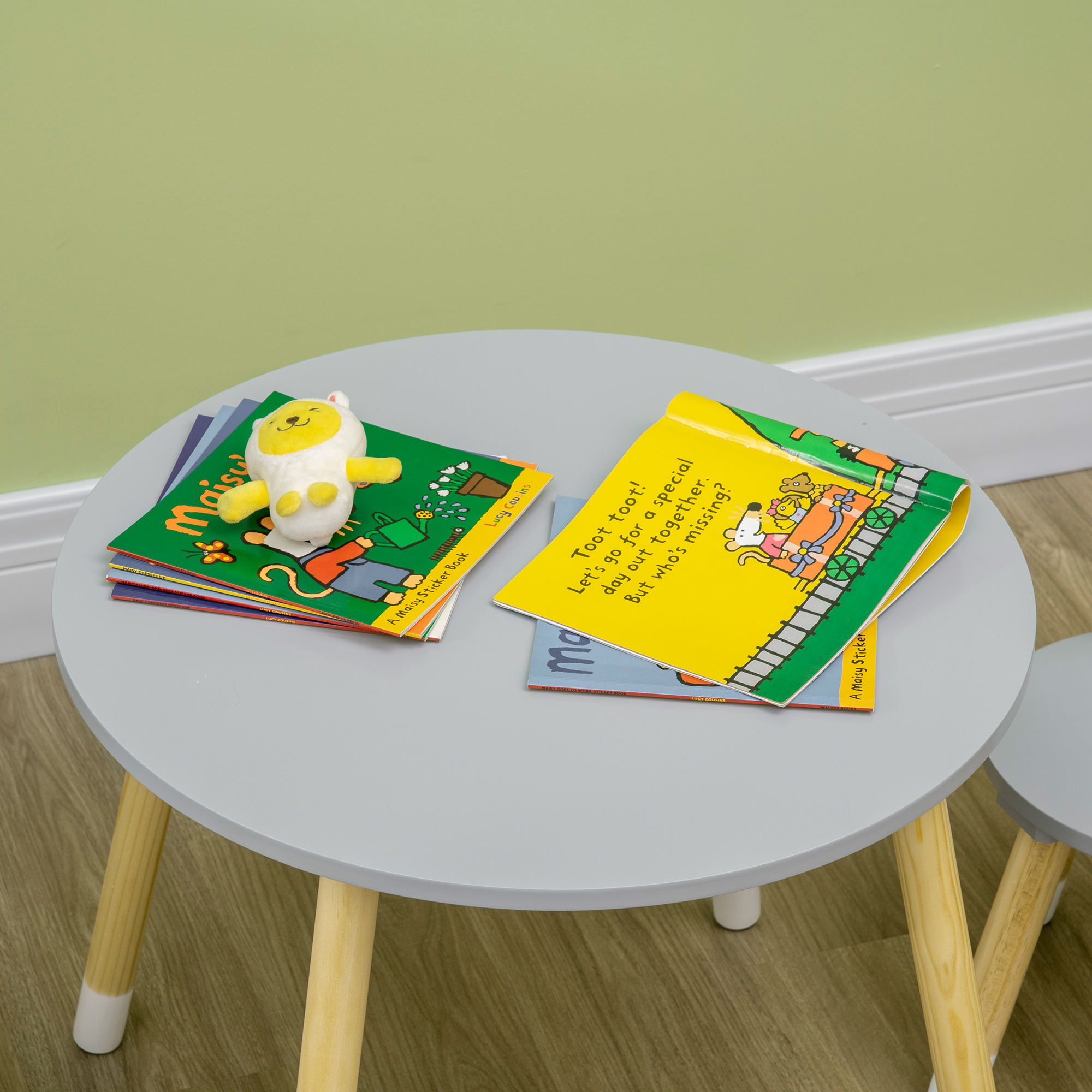 Un peluche está sobre libros en una mesa gris.