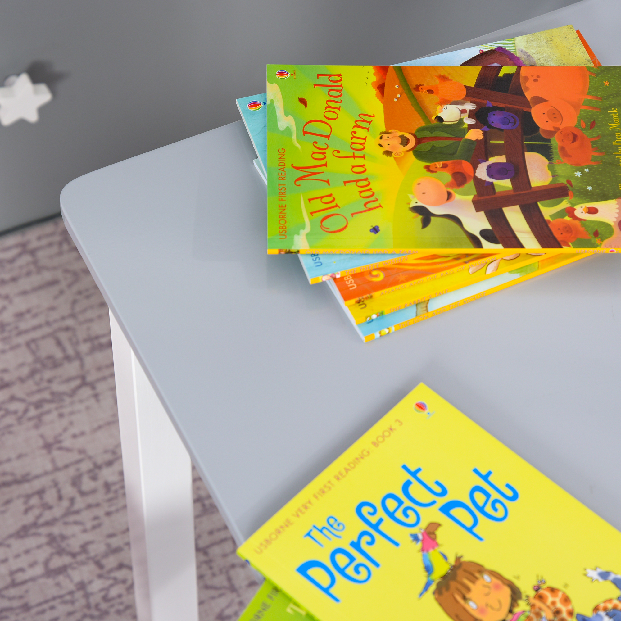 Una pila de libros infantiles sobre una mesa. Uno se titula 'Old MacDonald had a farm'.