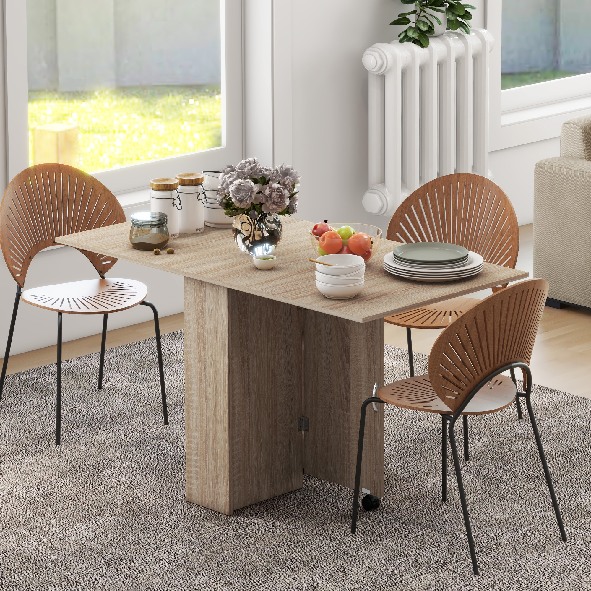 Una mesa de madera con sillas, frutero, flores y vajilla frente a una ventana.