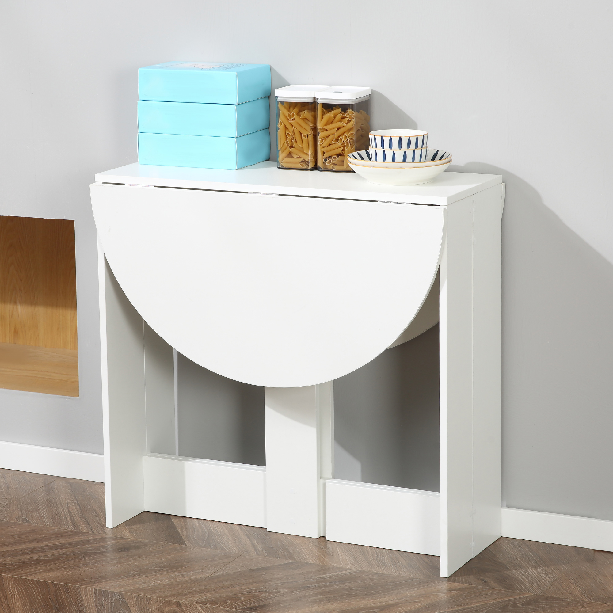 Una mesa extensible blanca con cajas azules, tarros de pasta y cuencos apilados.