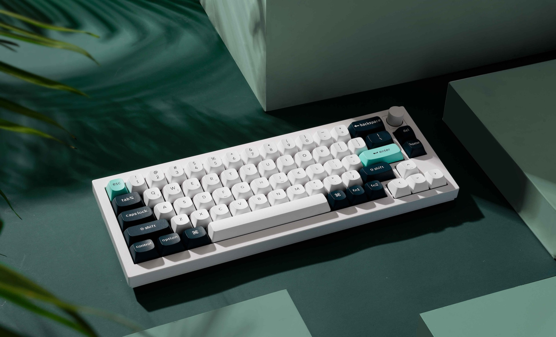 Biała klawiatura mechaniczna z turkusowymi i granatowymi akcentami na ciemnozielonej powierzchni.