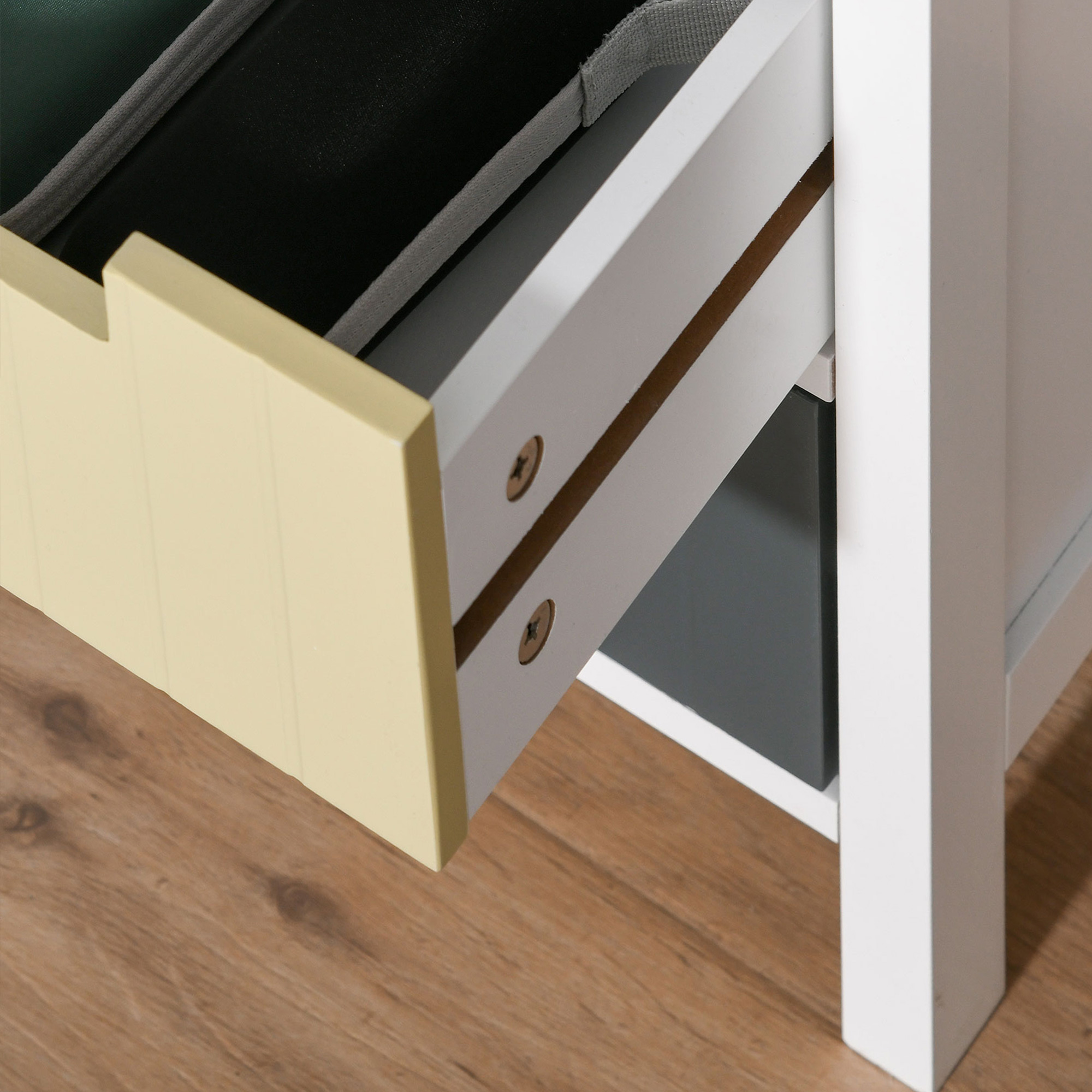 Un cajón amarillo claro sobre suelo de madera. El interior del cajón es visible con forro de tela gris.