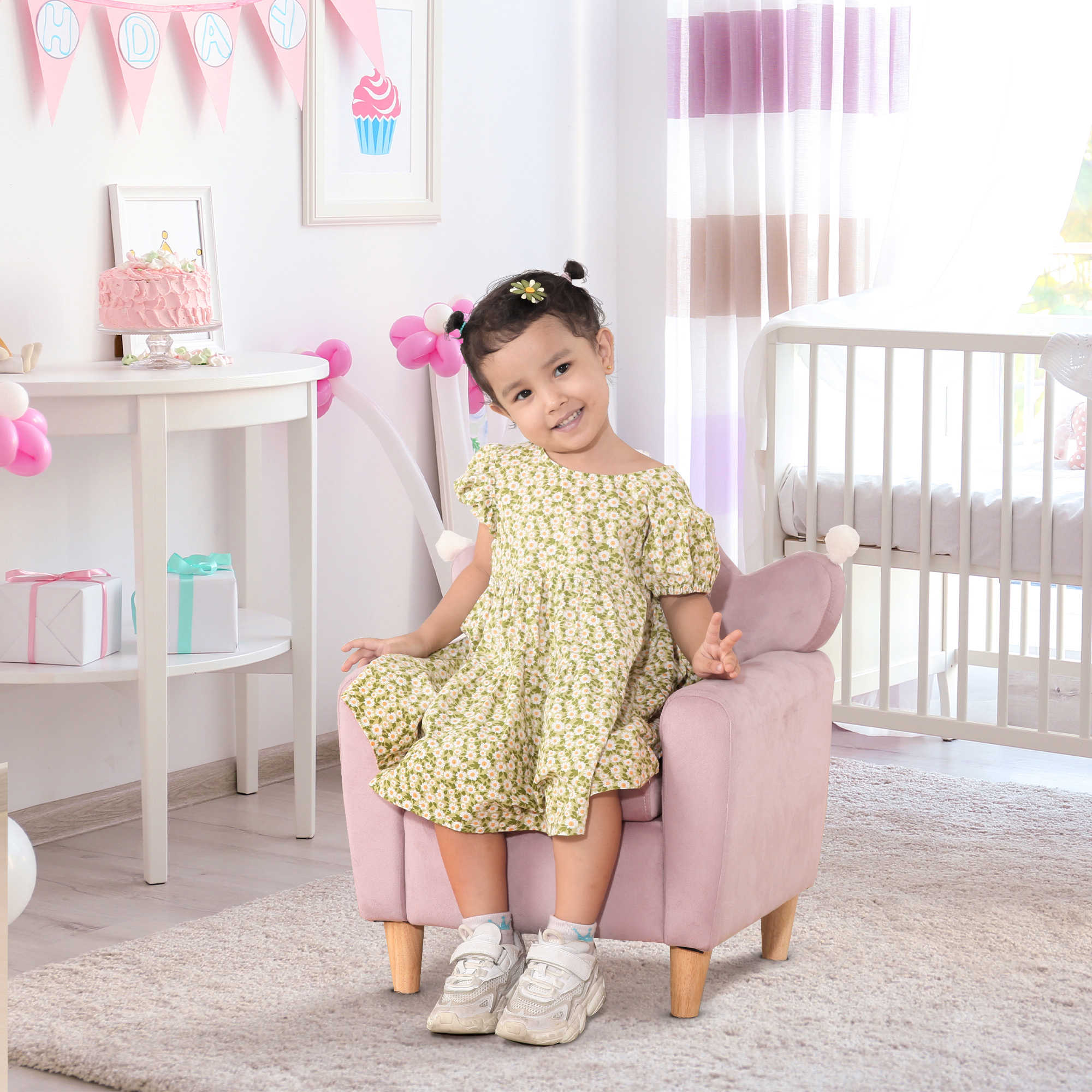 Una niña con vestido floreado se sienta en una silla rosa cerca de regalos y un pastel.