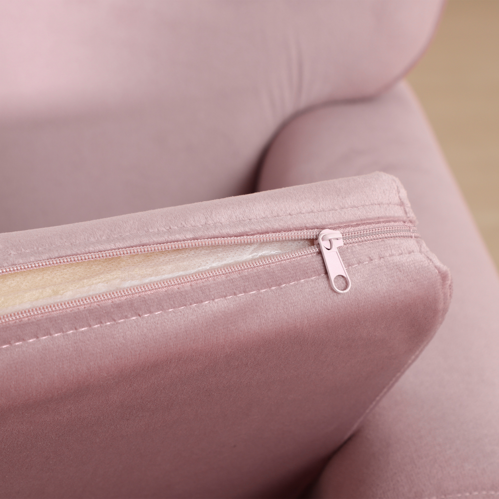 Una funda de sofá rosa con cremallera abierta que revela el relleno.