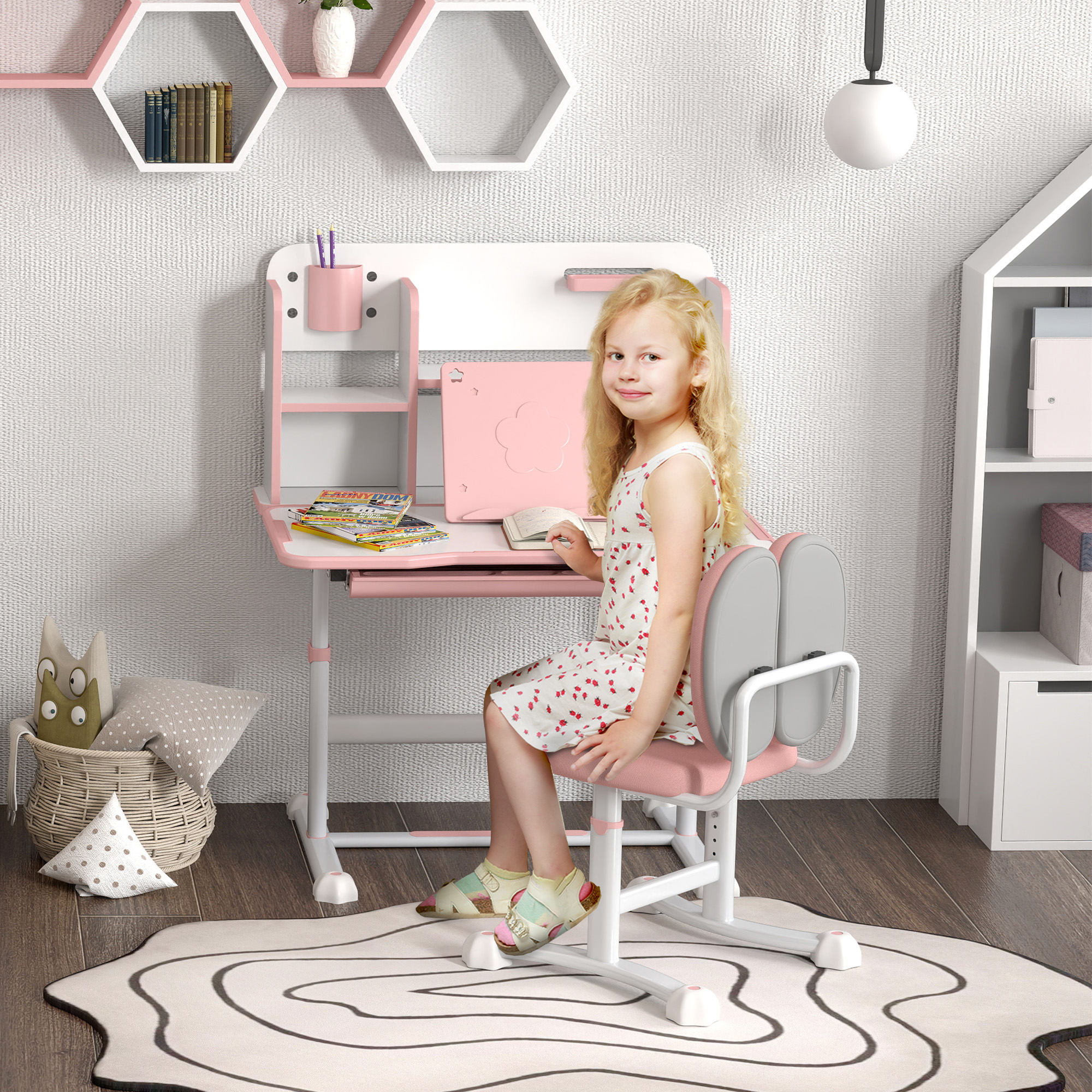 Una bambina bionda seduta a una scrivania rosa legge un libro.