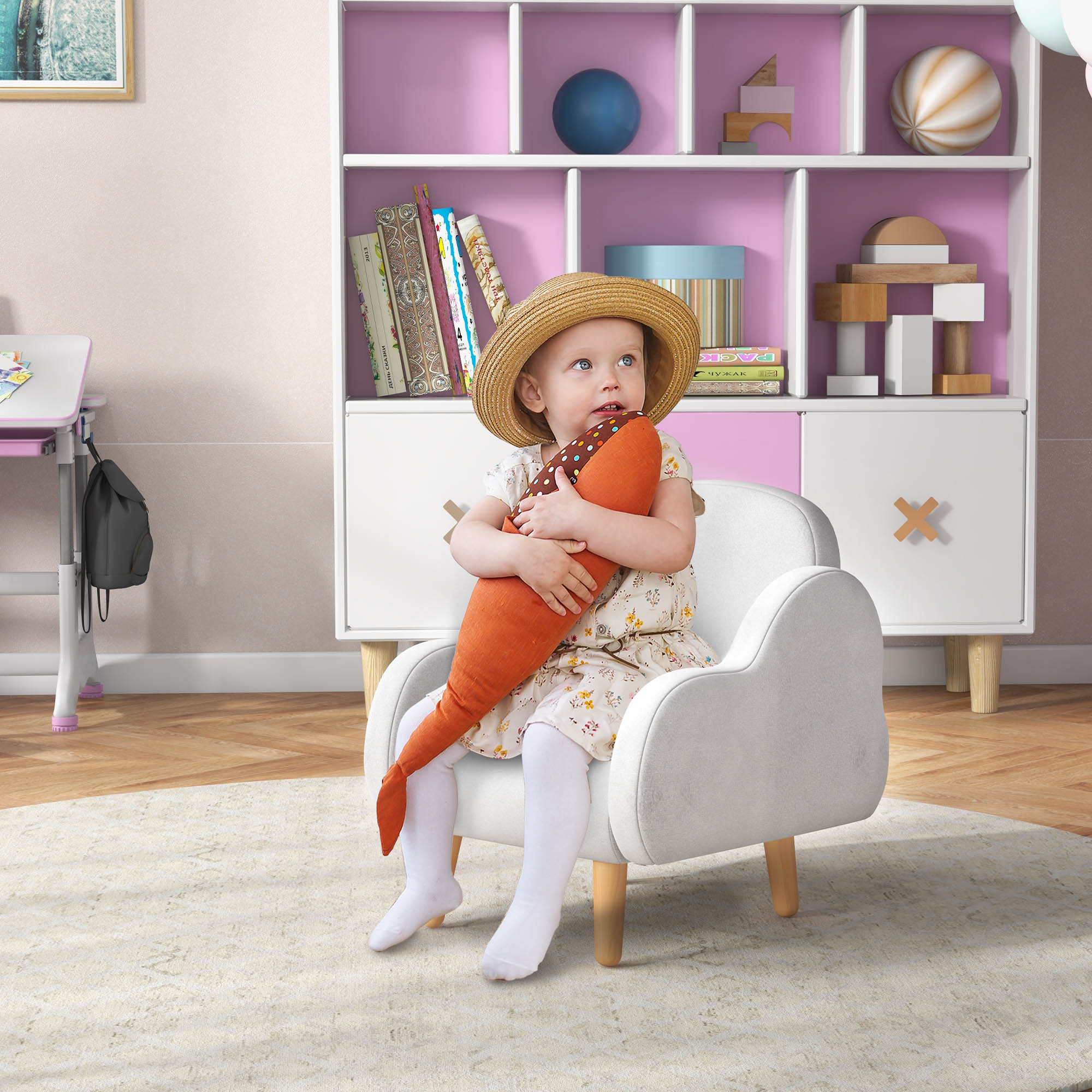 Una niña pequeña sentada en una silla con un juguete de zanahoria naranja.