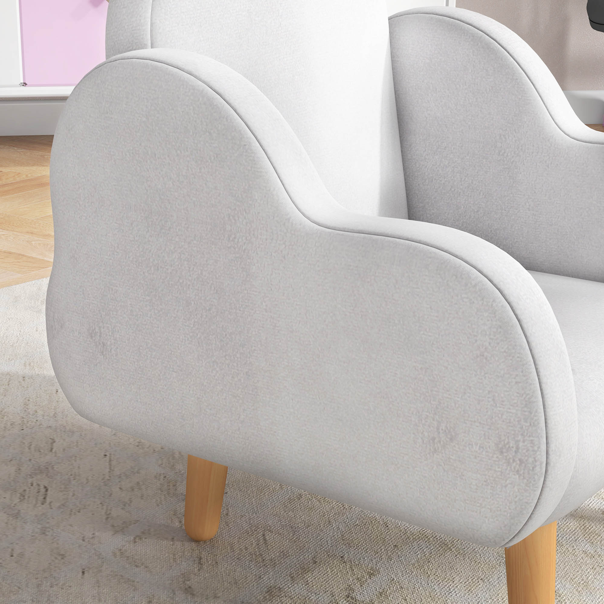 Un sillón tapizado de color claro con patas de madera sobre una alfombra.