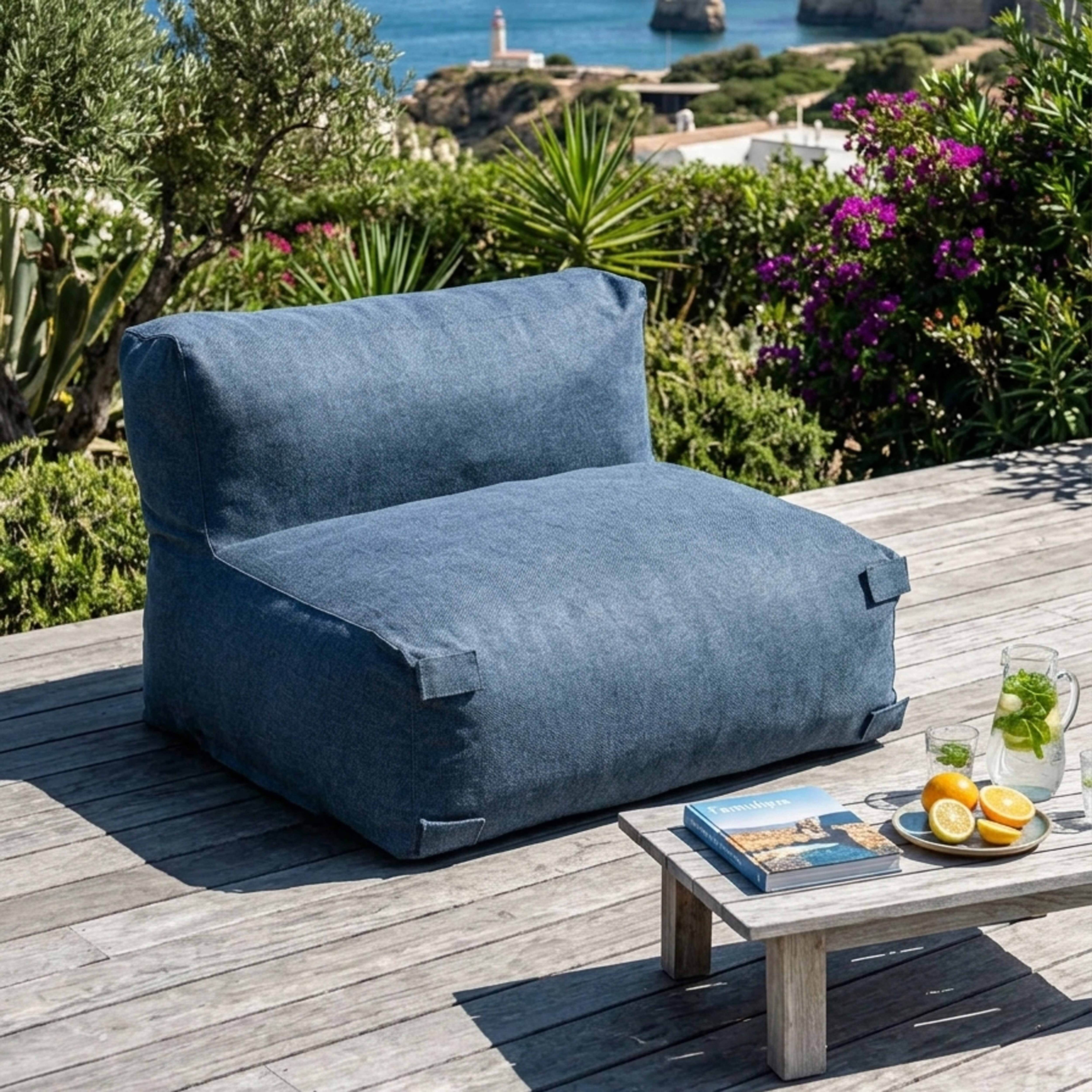 Ein blauer Sessel steht auf einer Holzterrasse mit Blick auf das Meer.