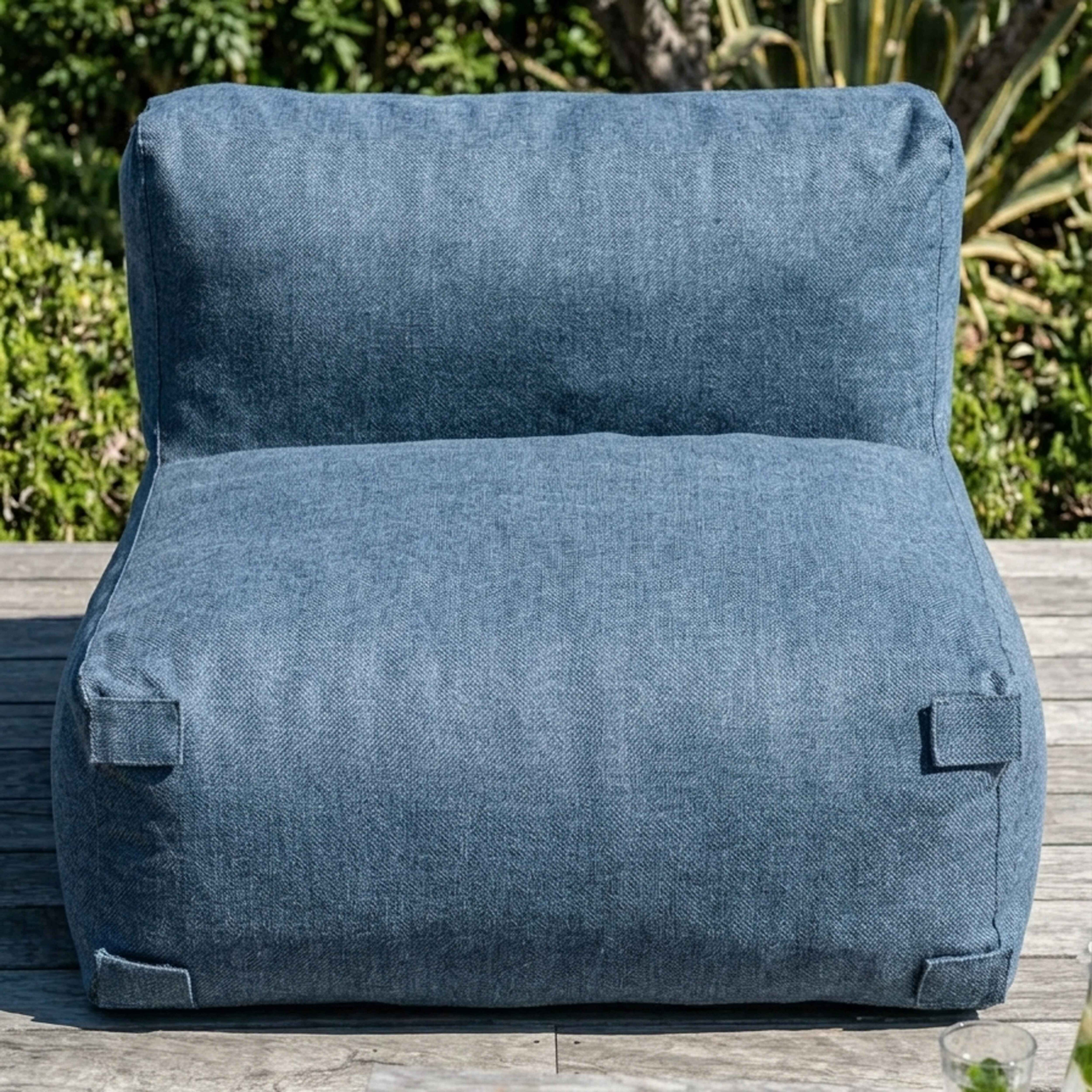 Ein blauer Sessel auf einer Holzterrasse, mit Pflanzen im Hintergrund.
