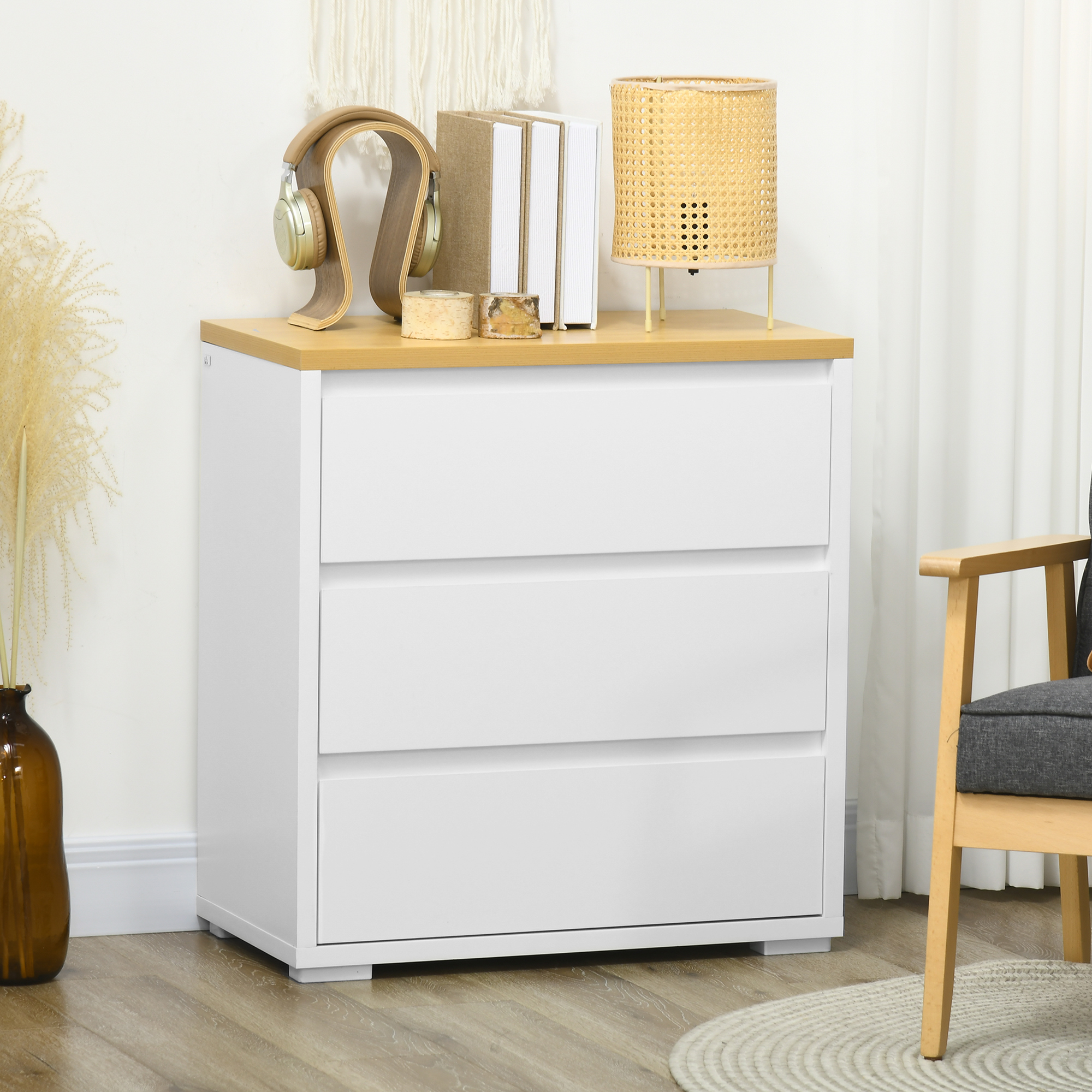 Una cómoda blanca con tapa de madera, auriculares, libros y lámpara.
