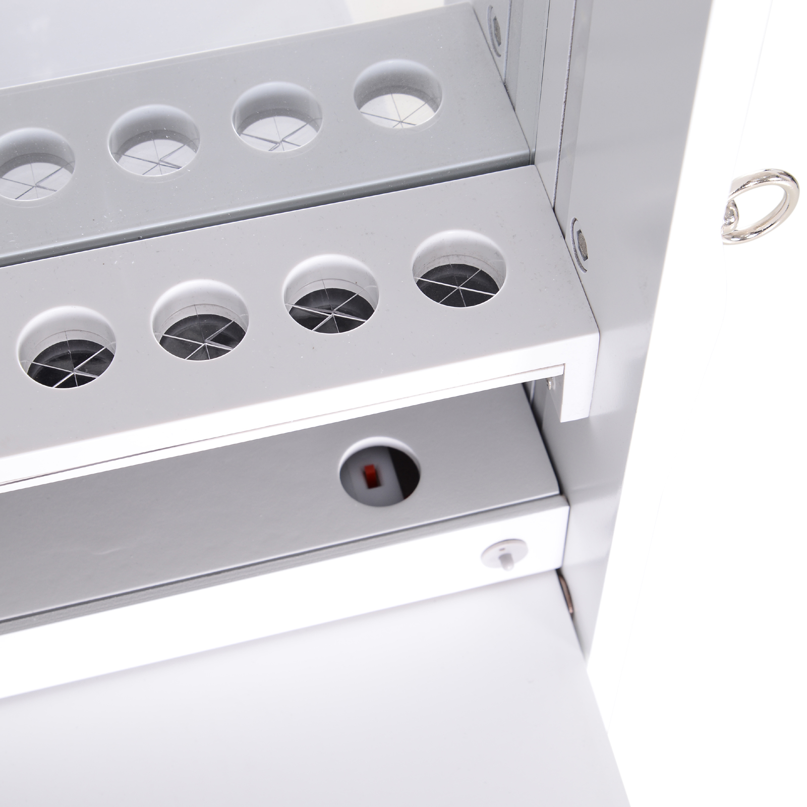 Gabinete metálico gris con aberturas redondas y un asa de anillo plateada.