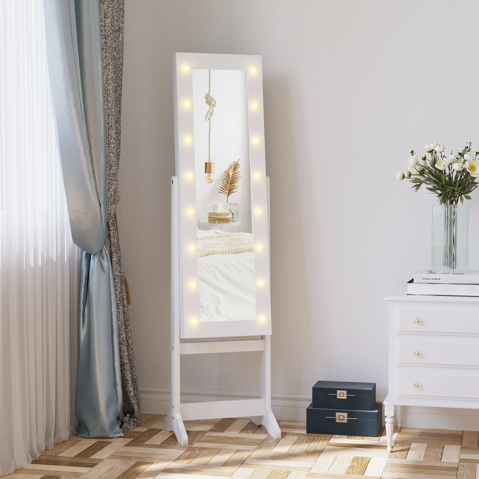 Un espejo de tocador blanco con luces, junto a una cómoda con flores.