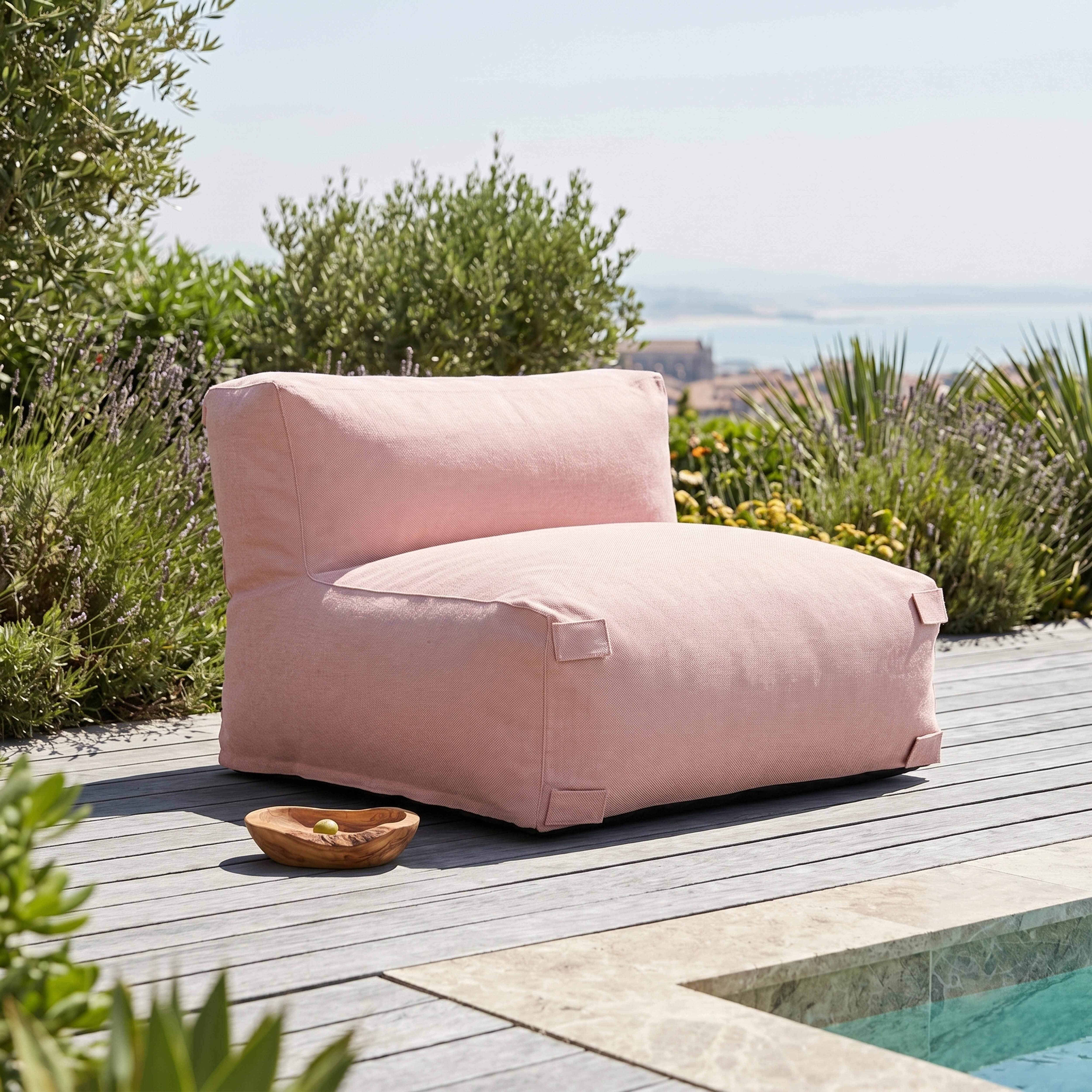 Ein rosafarbener Sessel steht auf einer Holzterrasse neben einem Pool.