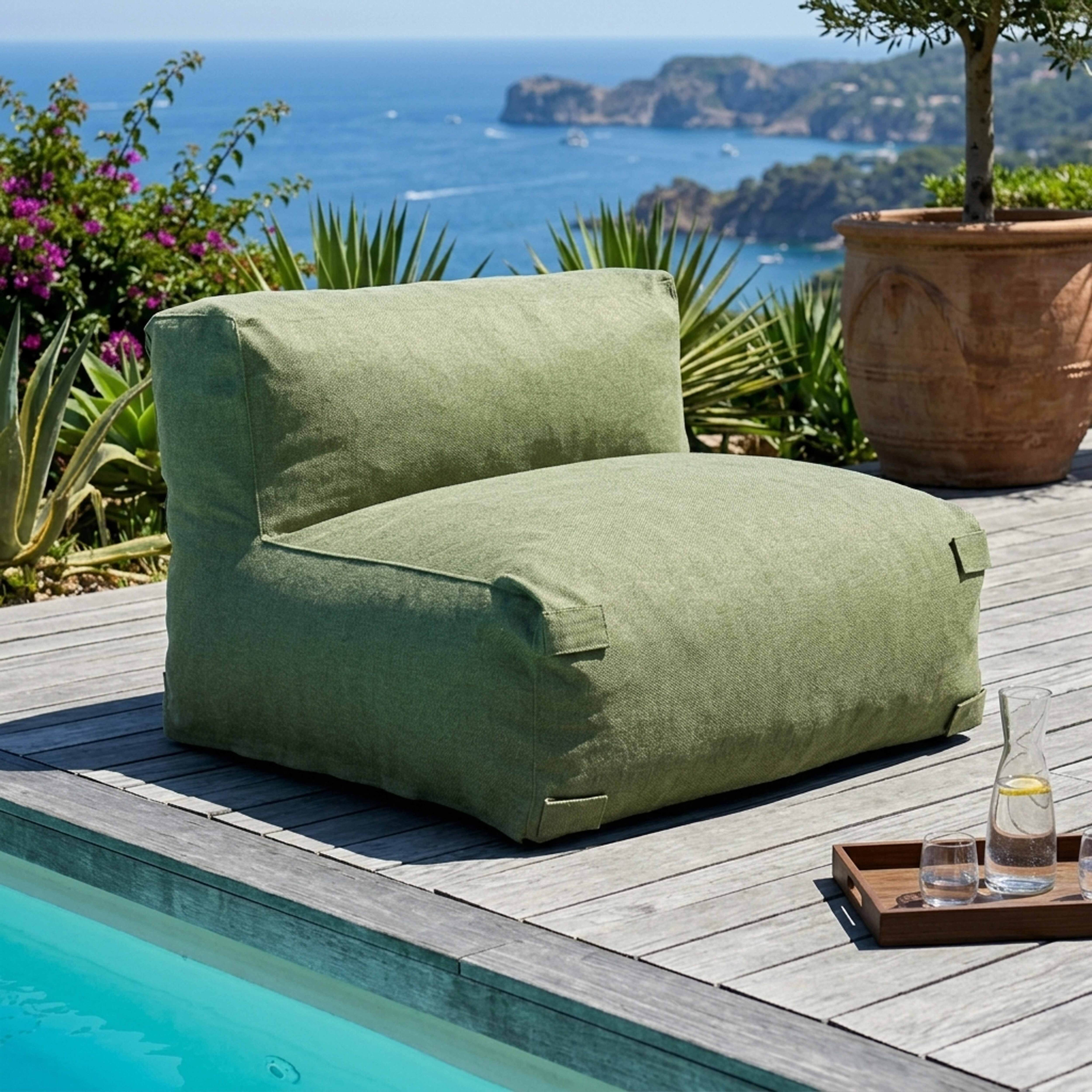 Ein grüner Sessel am Pool mit Blick auf das Meer und die Küste.