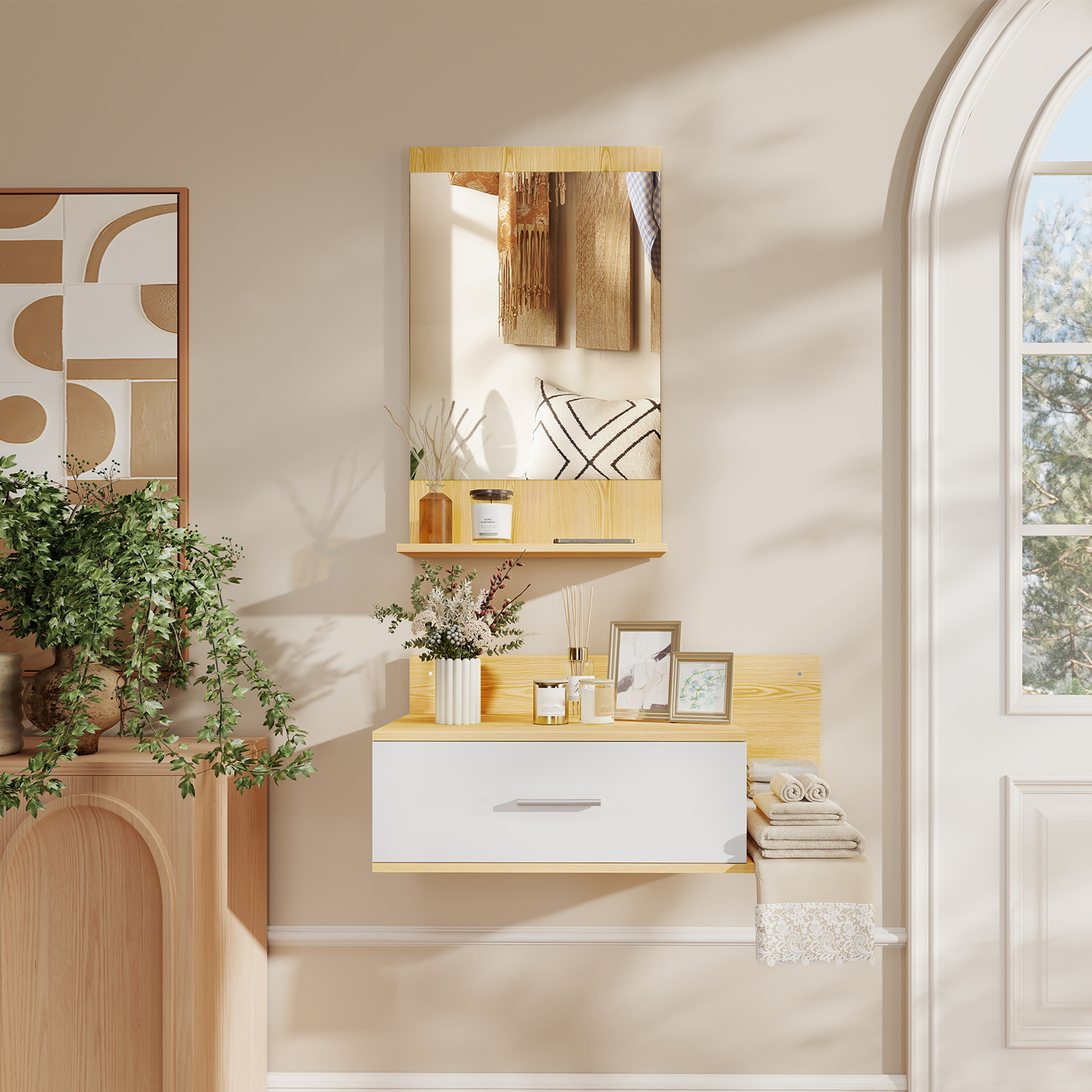 Un espejo de pared sobre un mueble cajonero blanco con estantes de madera, plantas y decoración.