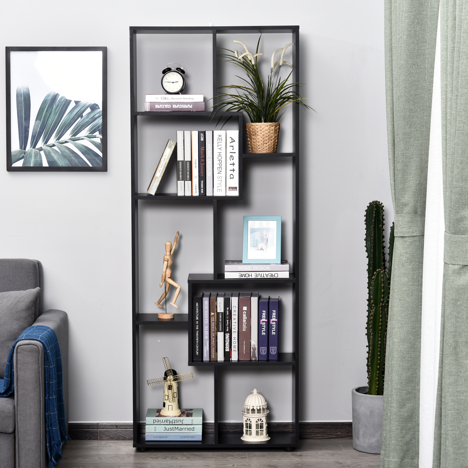 Estantería negra con libros, plantas, decoración y un cuadro.
