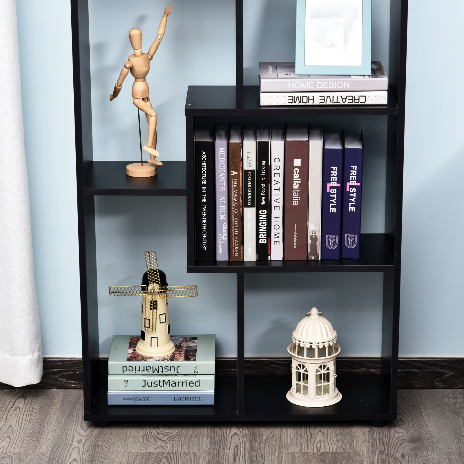 Estantería negra con libros, decoraciones y figura de madera.