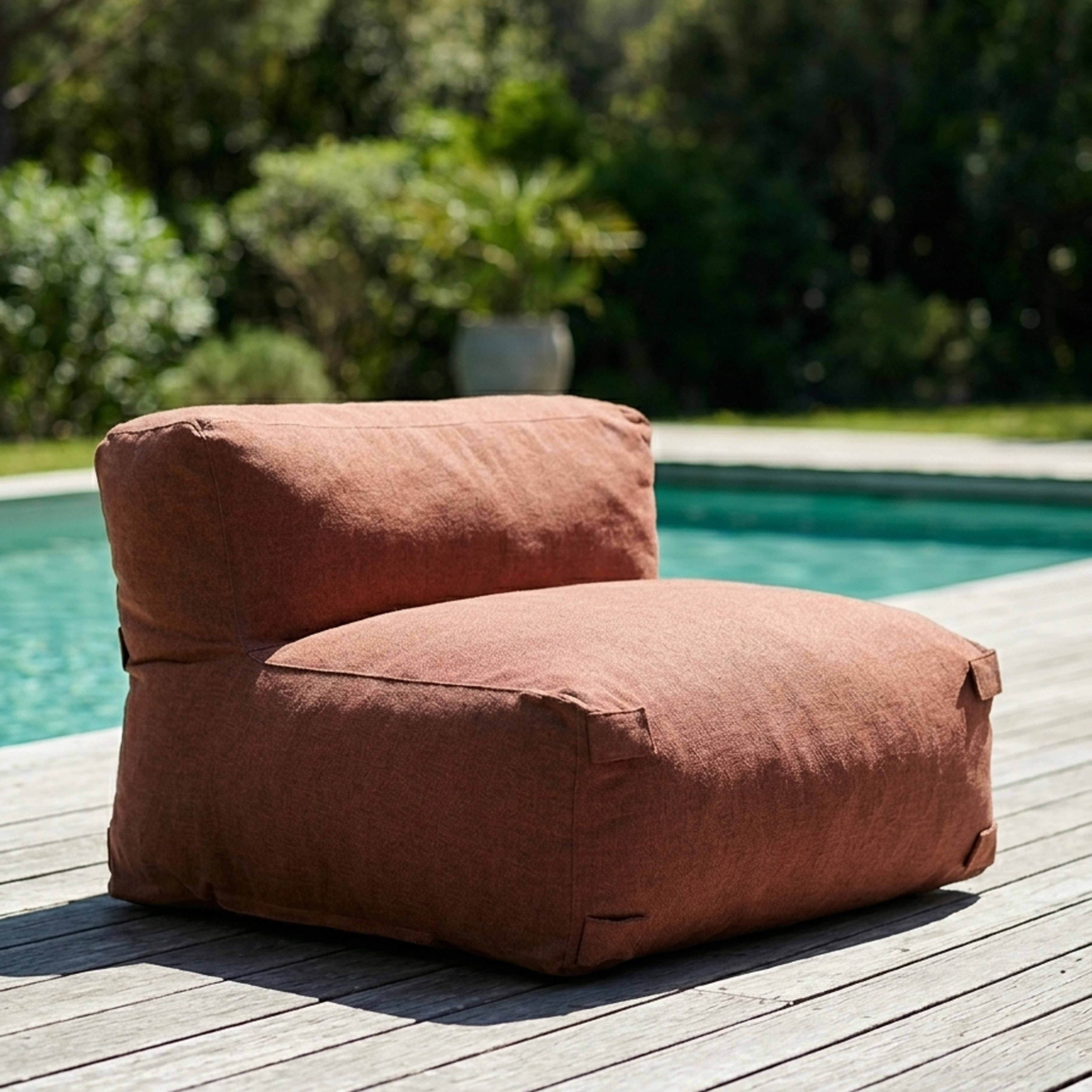Ein brauner Sessel steht auf einer Holzterrasse neben einem Pool.