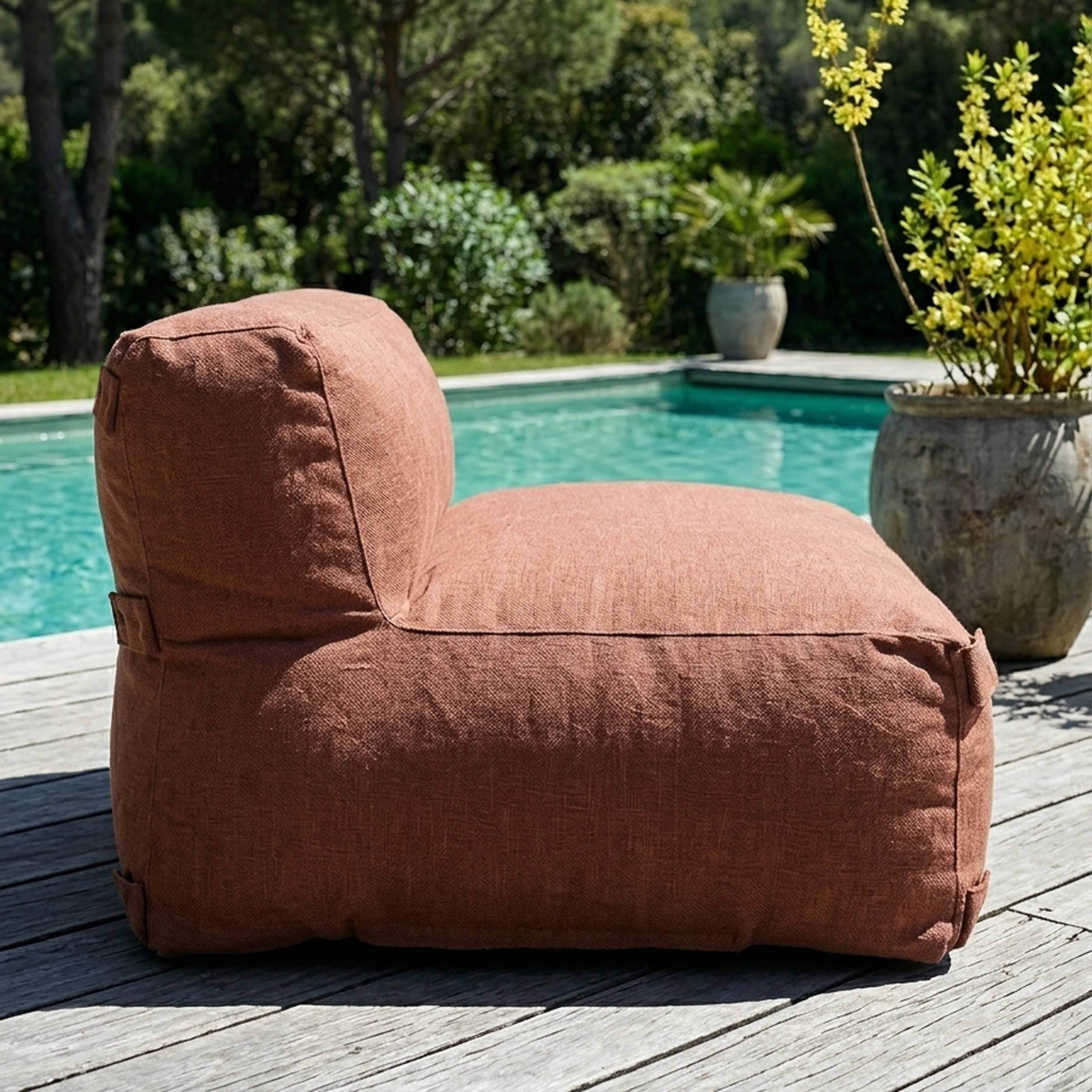 Ein brauner Sitzsack steht auf einer Holzterrasse neben einem Pool.