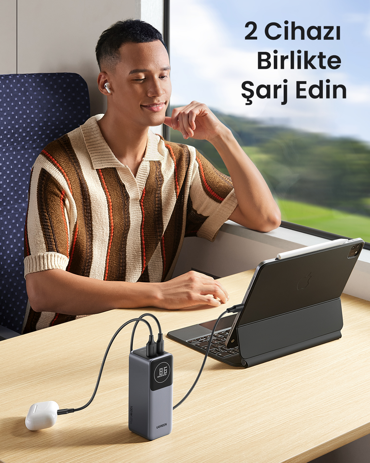 Mężczyzna w pociągu ładuje powerbank, słuchawki AirPods i tablet.