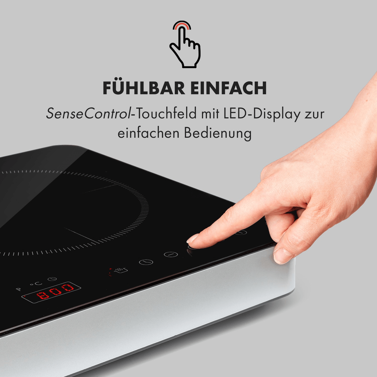 Una mano aziona un piano cottura a induzione con display touch e lettura digitale rossa.