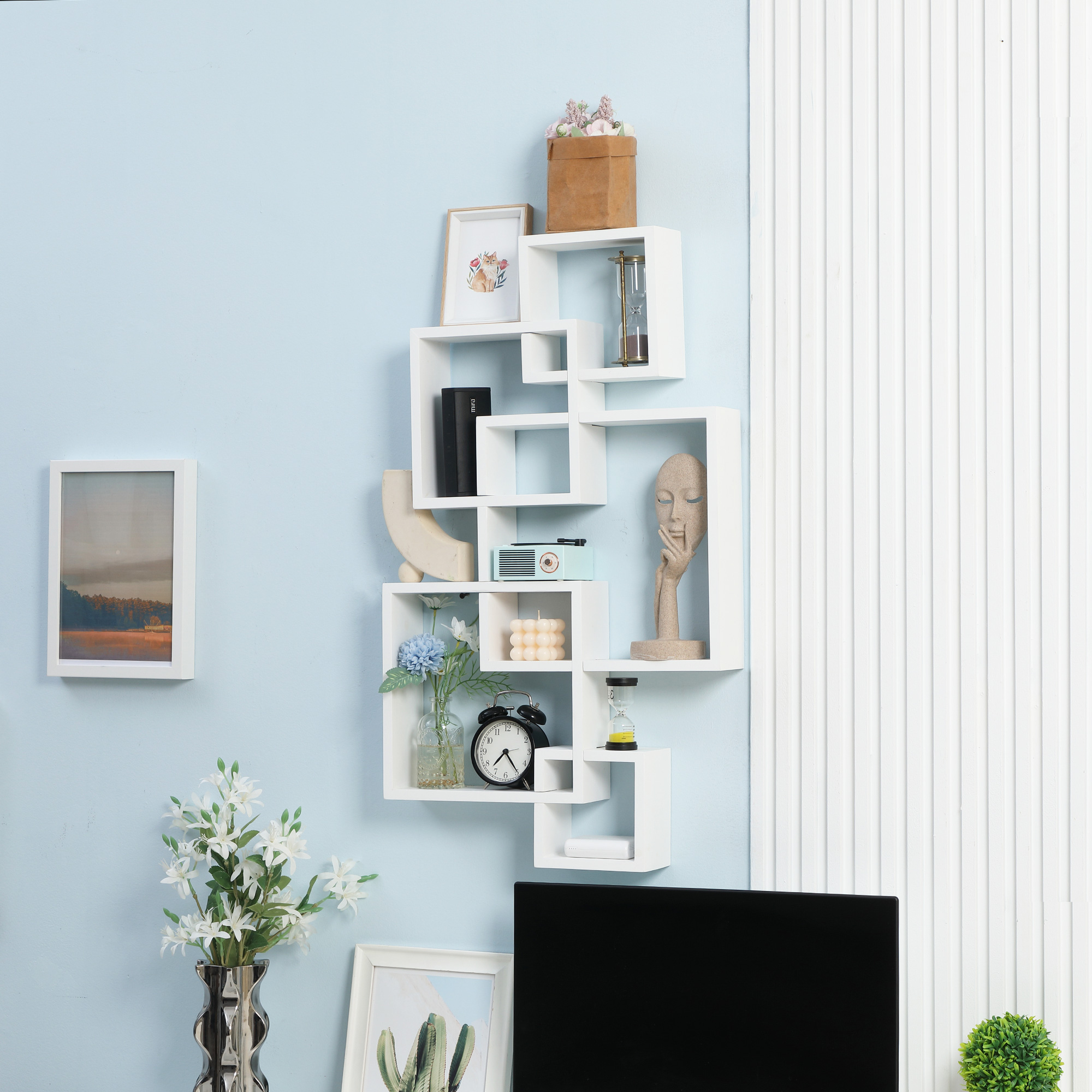 Estanterías cúbicas blancas con objetos decorativos en pared azul.