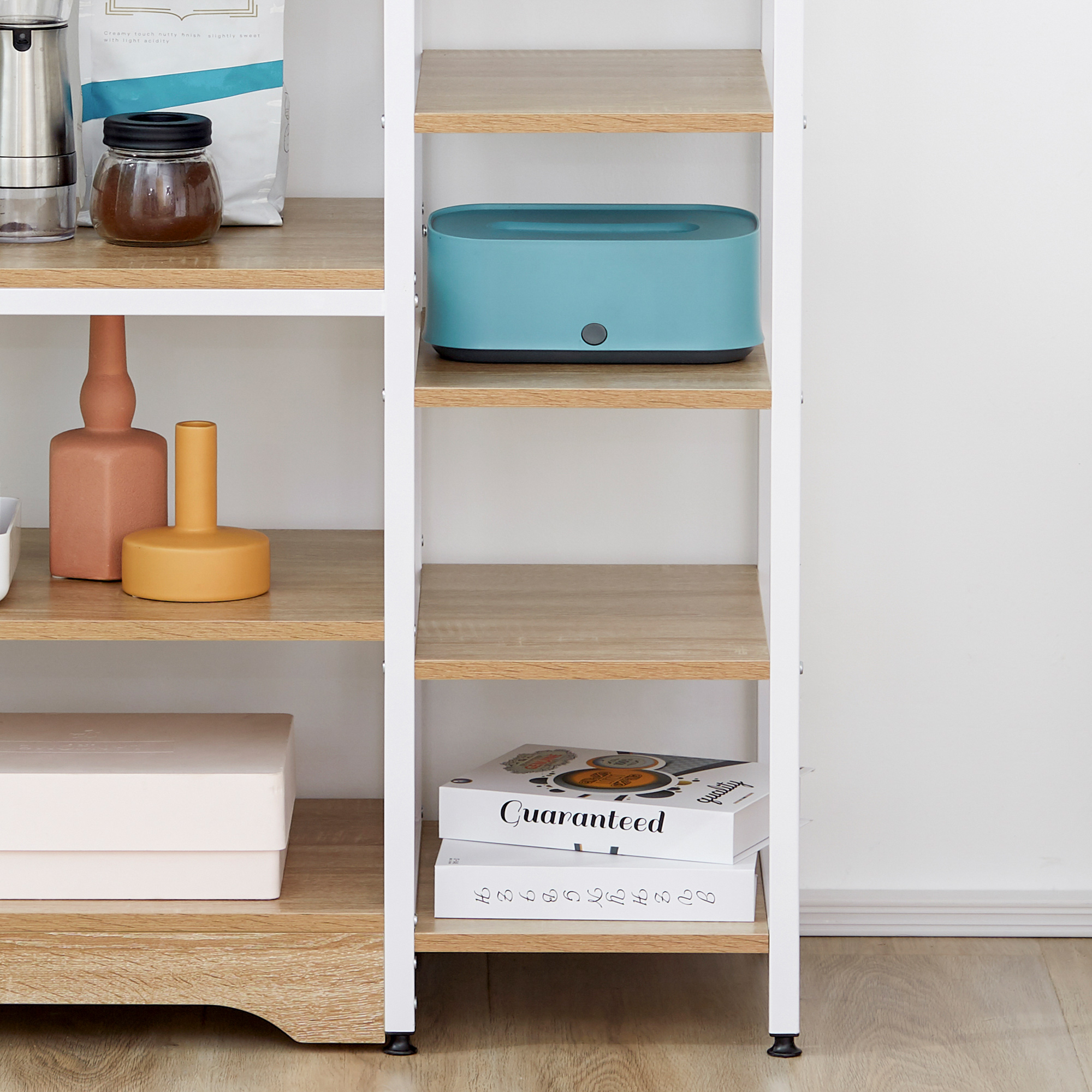 Estantería con objetos: cafetera, tarro, caja azul, jarrones, libros.