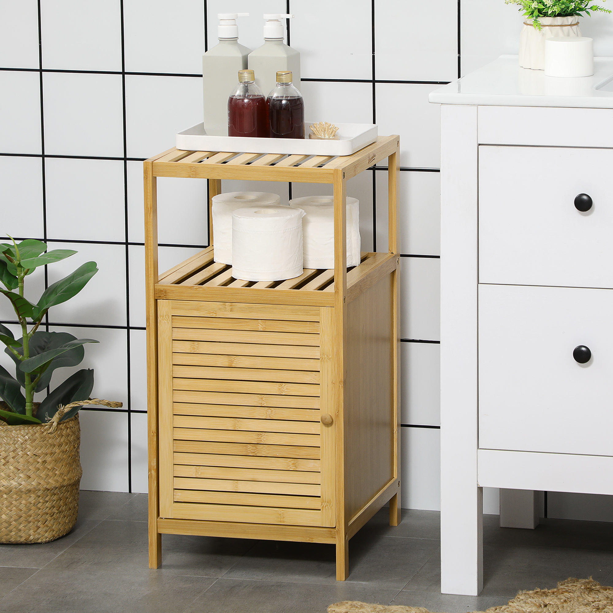 Un mueble de baño de bambú con 2 estantes, una puerta y rollos de papel higiénico.