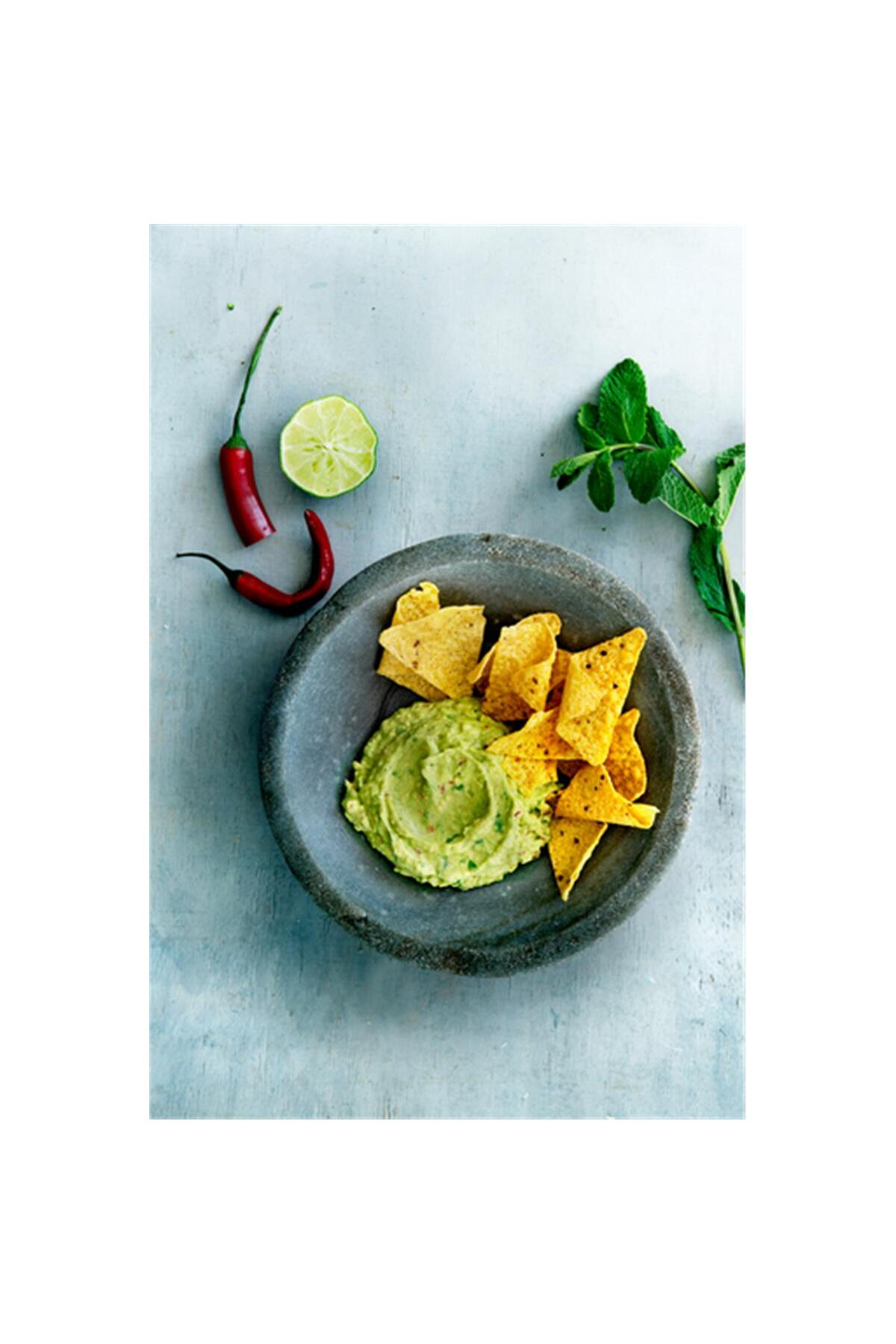 Guacamole z chipsami tortilla w misce, udekorowane chili, limonką i miętą.