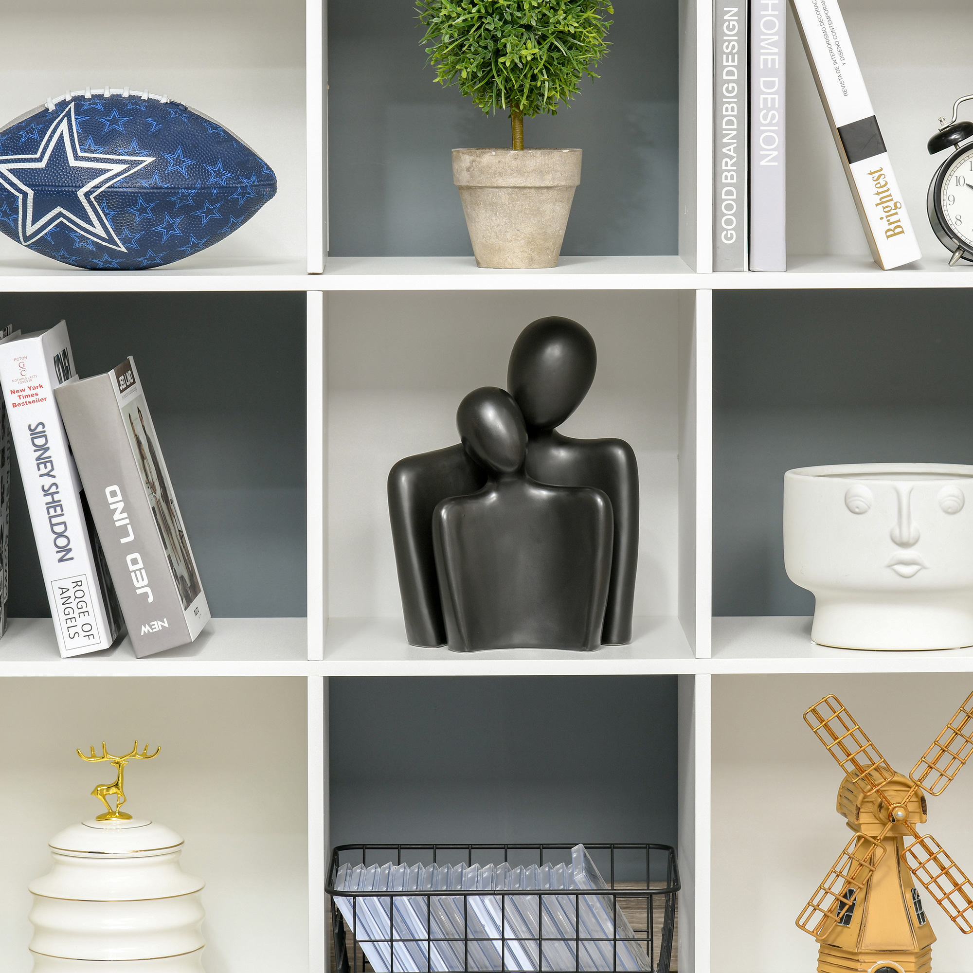 Un balón de fútbol americano de los Dallas Cowboys descansa en un estante entre libros y un reloj.