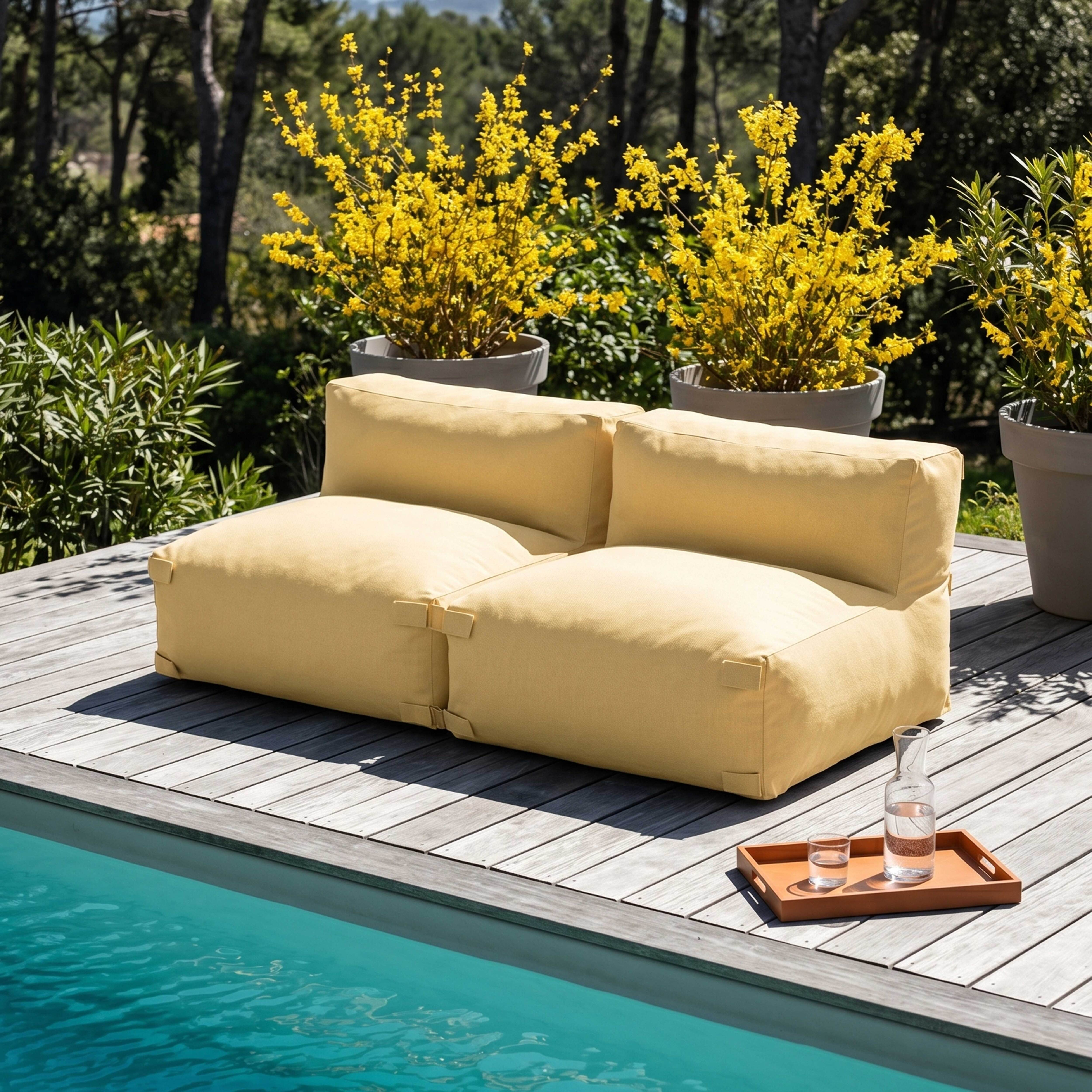 Ein gelbes Outdoor-Sofa steht auf einer Holzterrasse neben einem Pool.