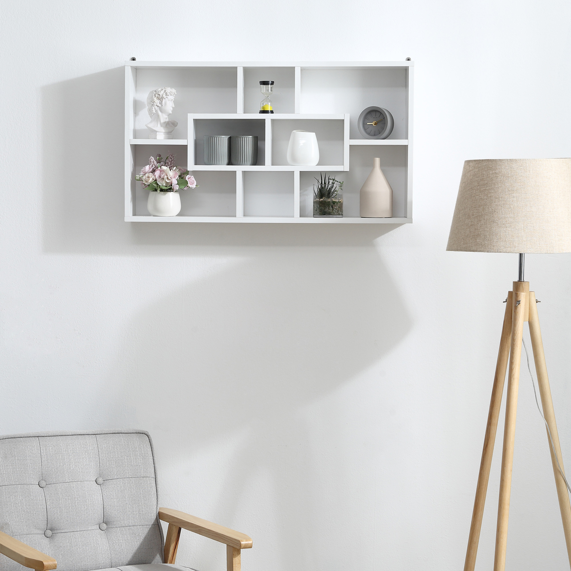 Una estantería blanca con decoraciones, un sillón y una lámpara de pie.