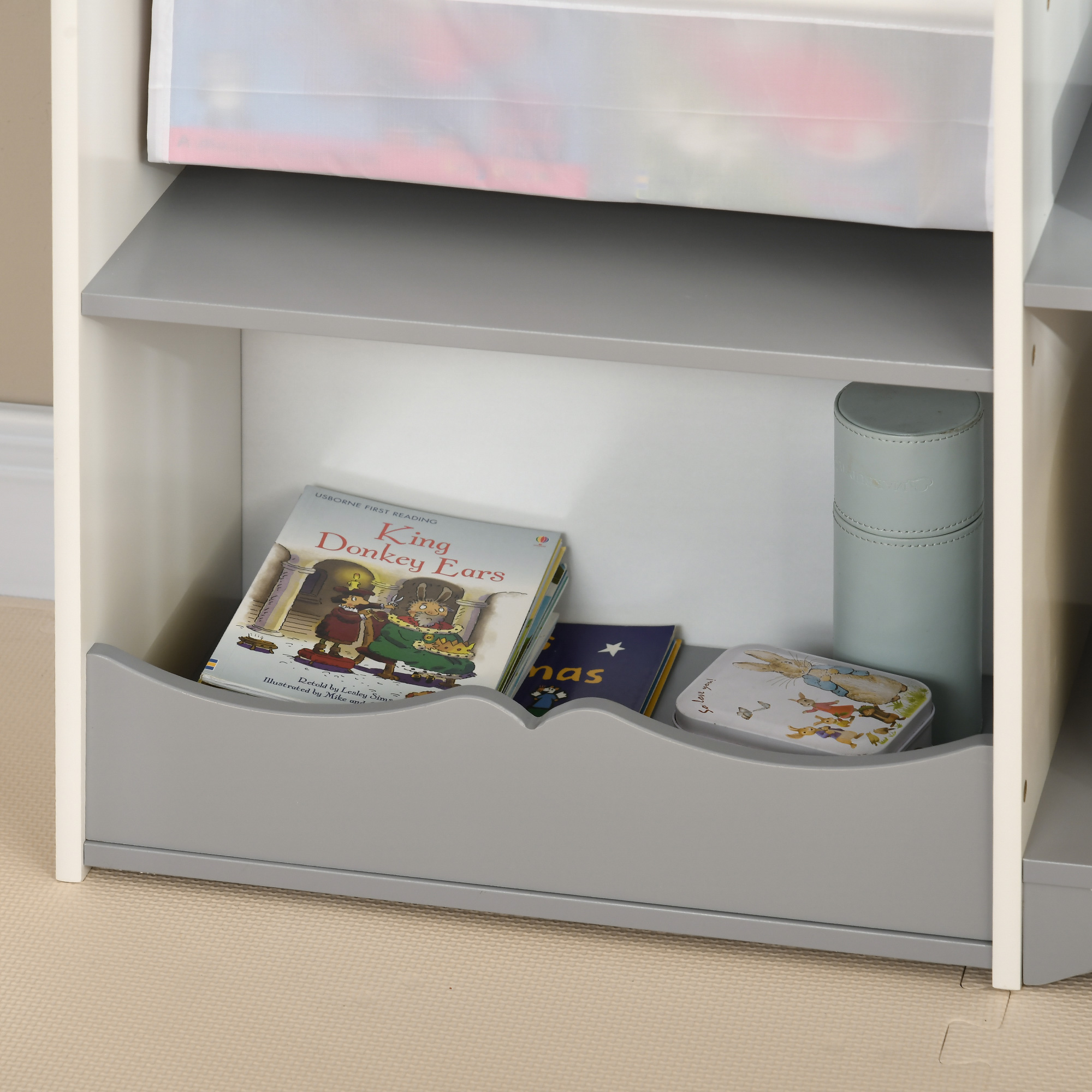 Un estante tiene libros, una lata y un cilindro.