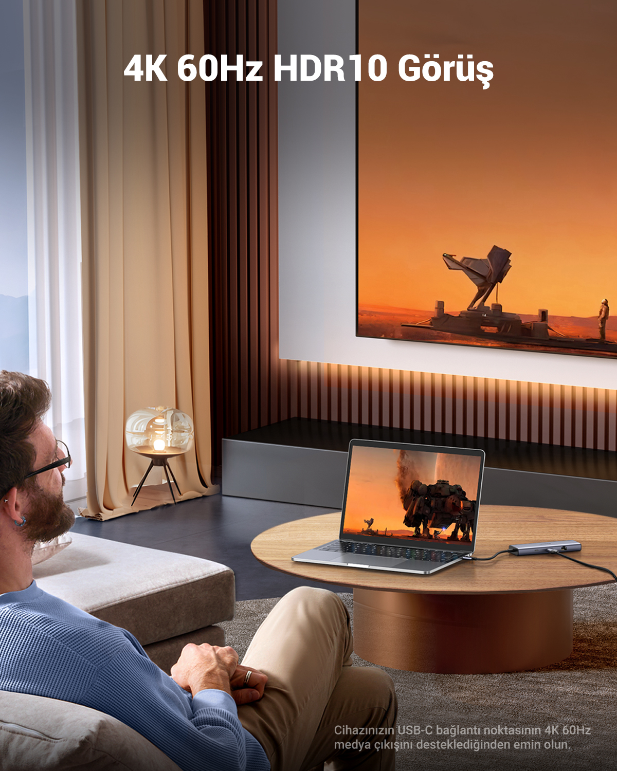 Mężczyzna siedzi na sofie, patrzy na laptopa wyświetlającego treści 4K HDR10.