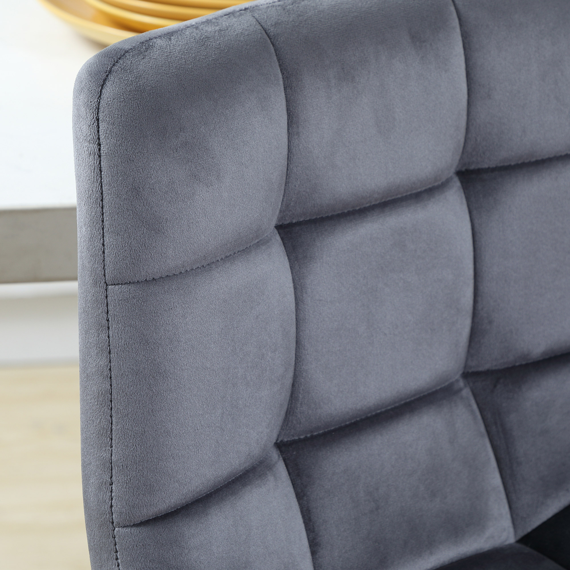 Silla tapizada gris con capitoné y cojines superpuestos.