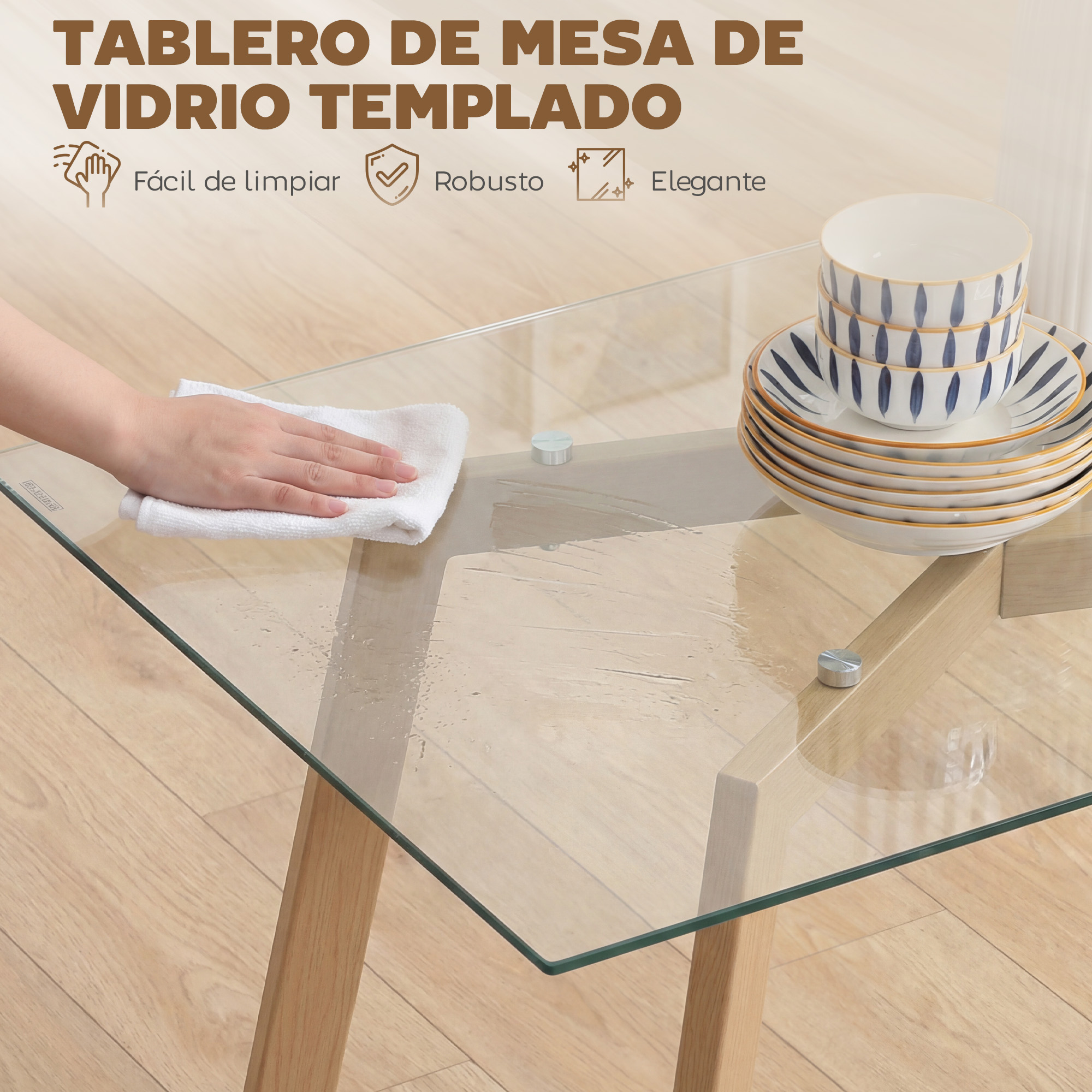 Una mano limpia una mesa de vidrio con un paño blanco. Platos y cuencos apilados.
