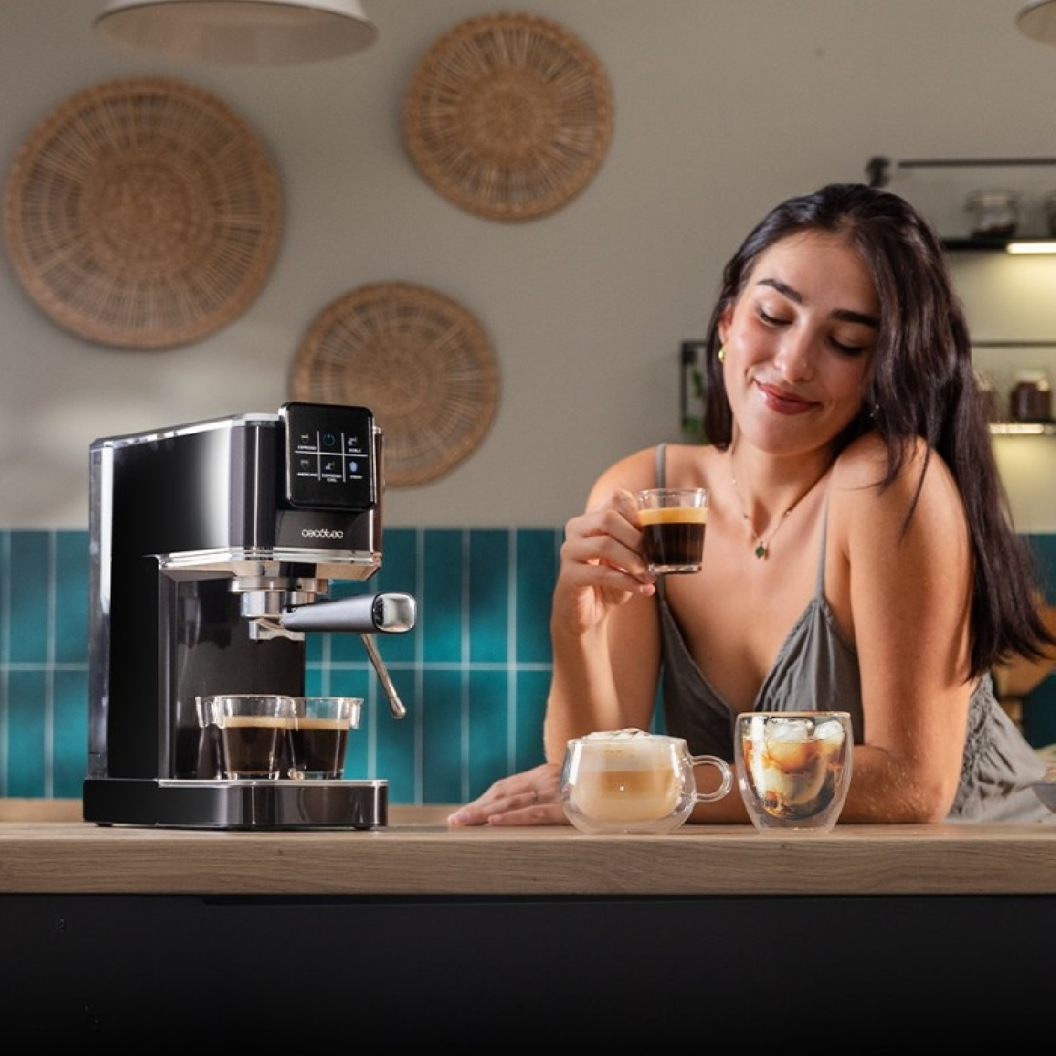 Una mujer disfruta de un espresso, junto a una cafetera y otras dos bebidas de café.