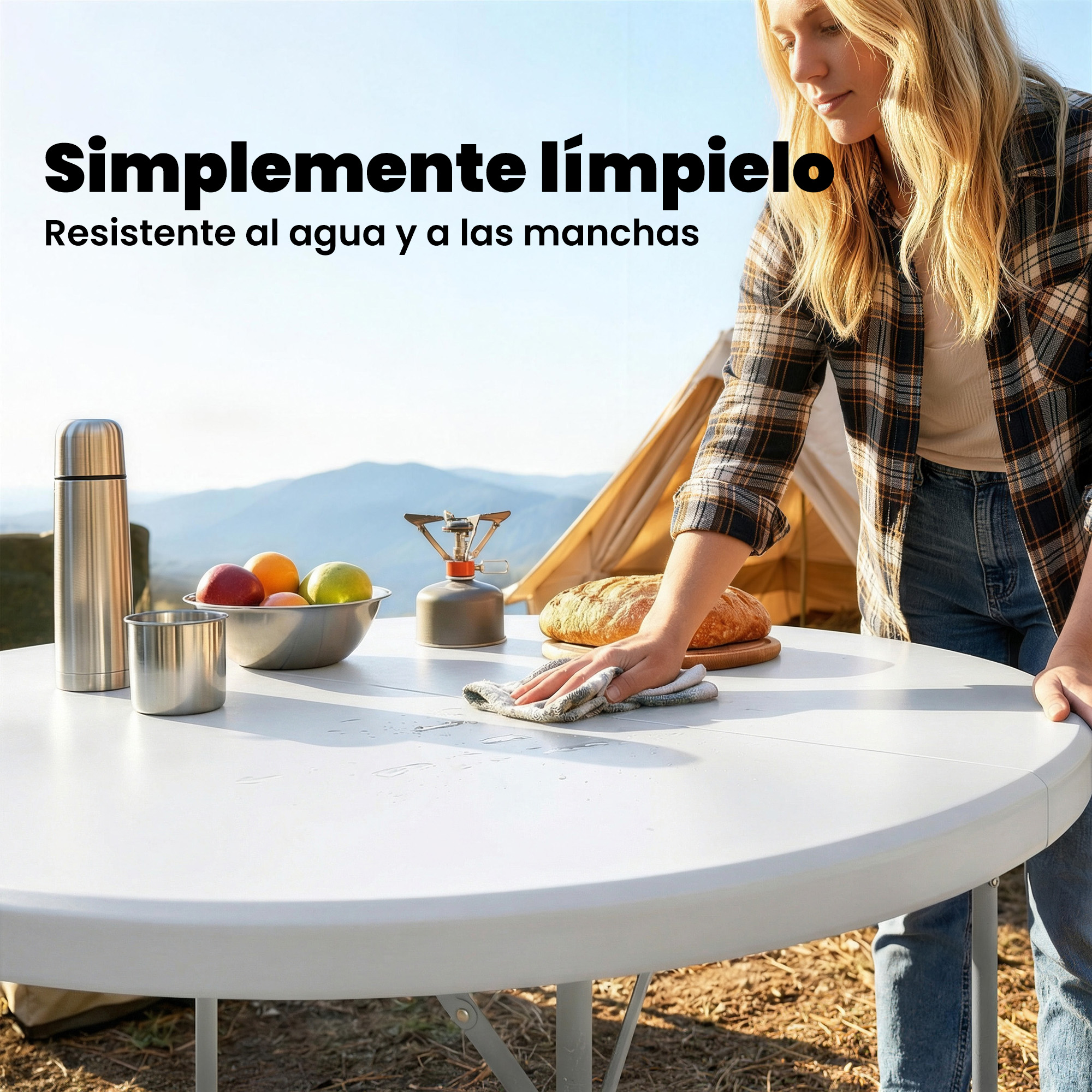 Mujer limpiando una mesa blanca con un paño, equipo de camping al fondo.