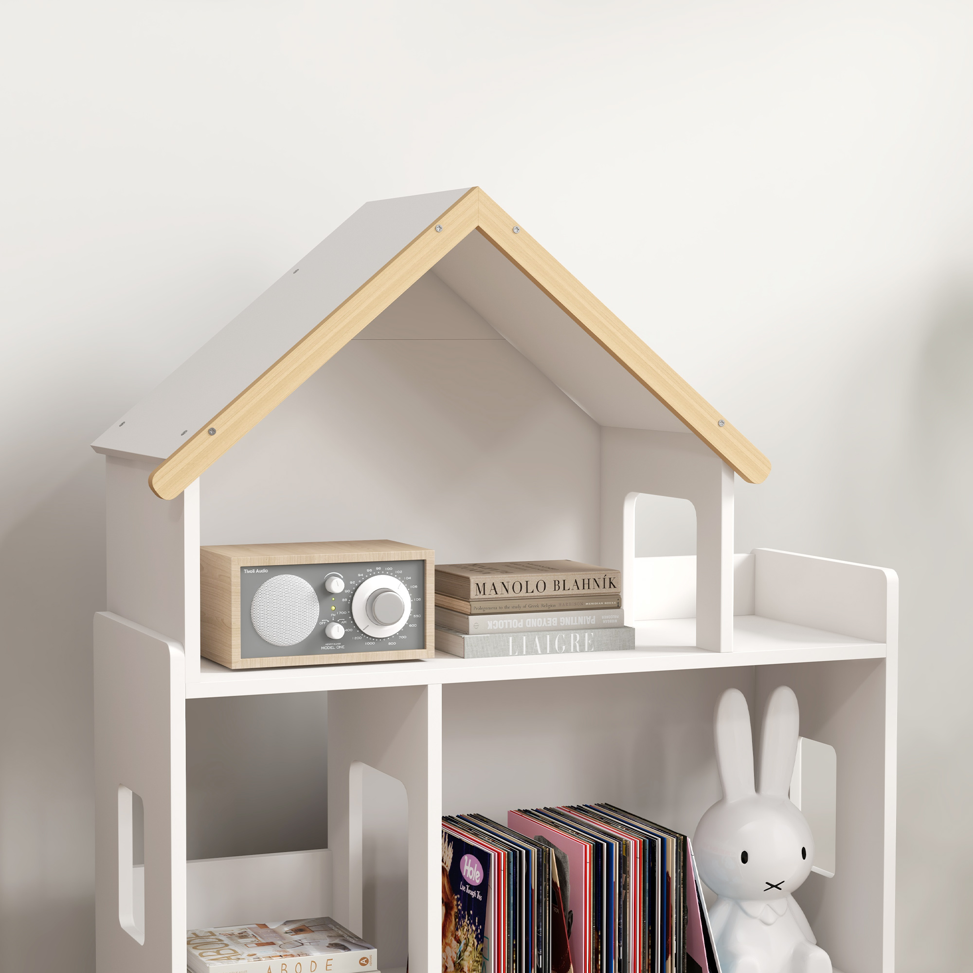 Estantería blanca con forma de casa de muñecas, radio, libros, discos y un conejo Miffy.