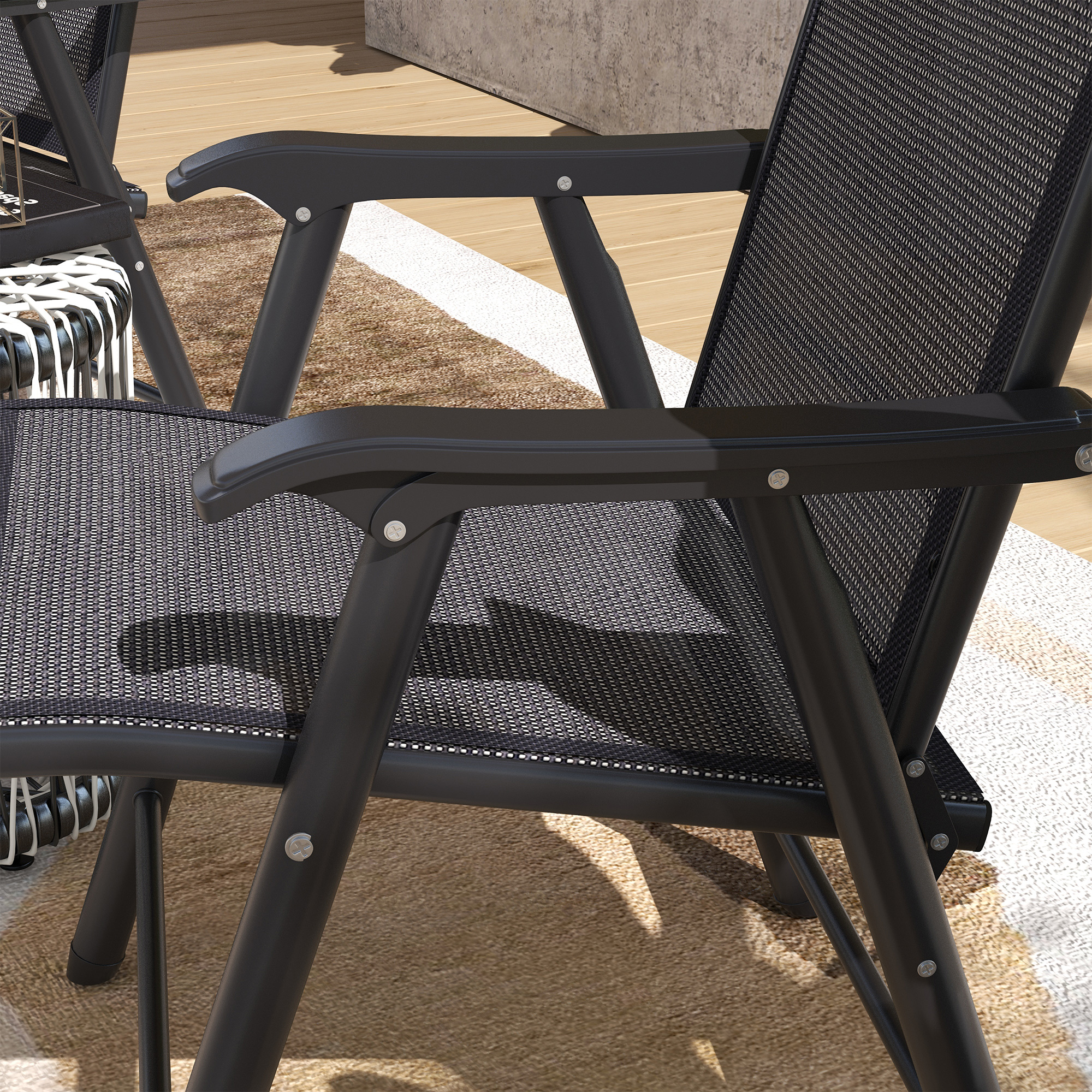 Una silla plegable negra con tejido de malla sobre una alfombra con tablones de madera.