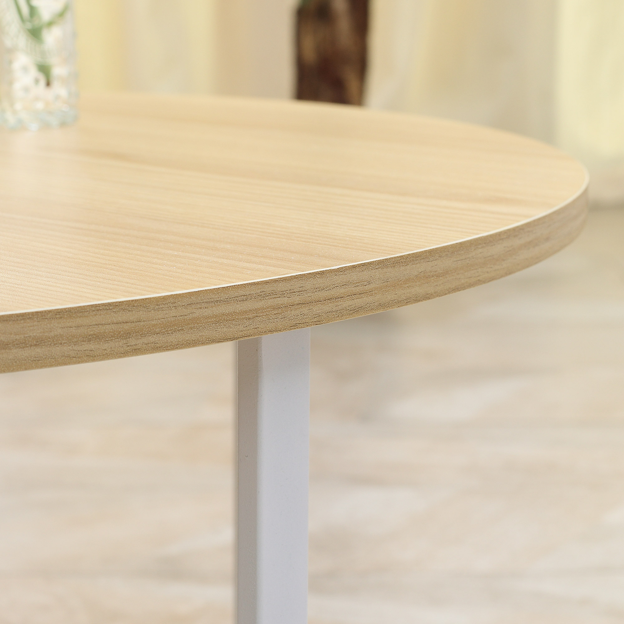 Mesa redonda de madera con pata blanca sobre fondo claro.