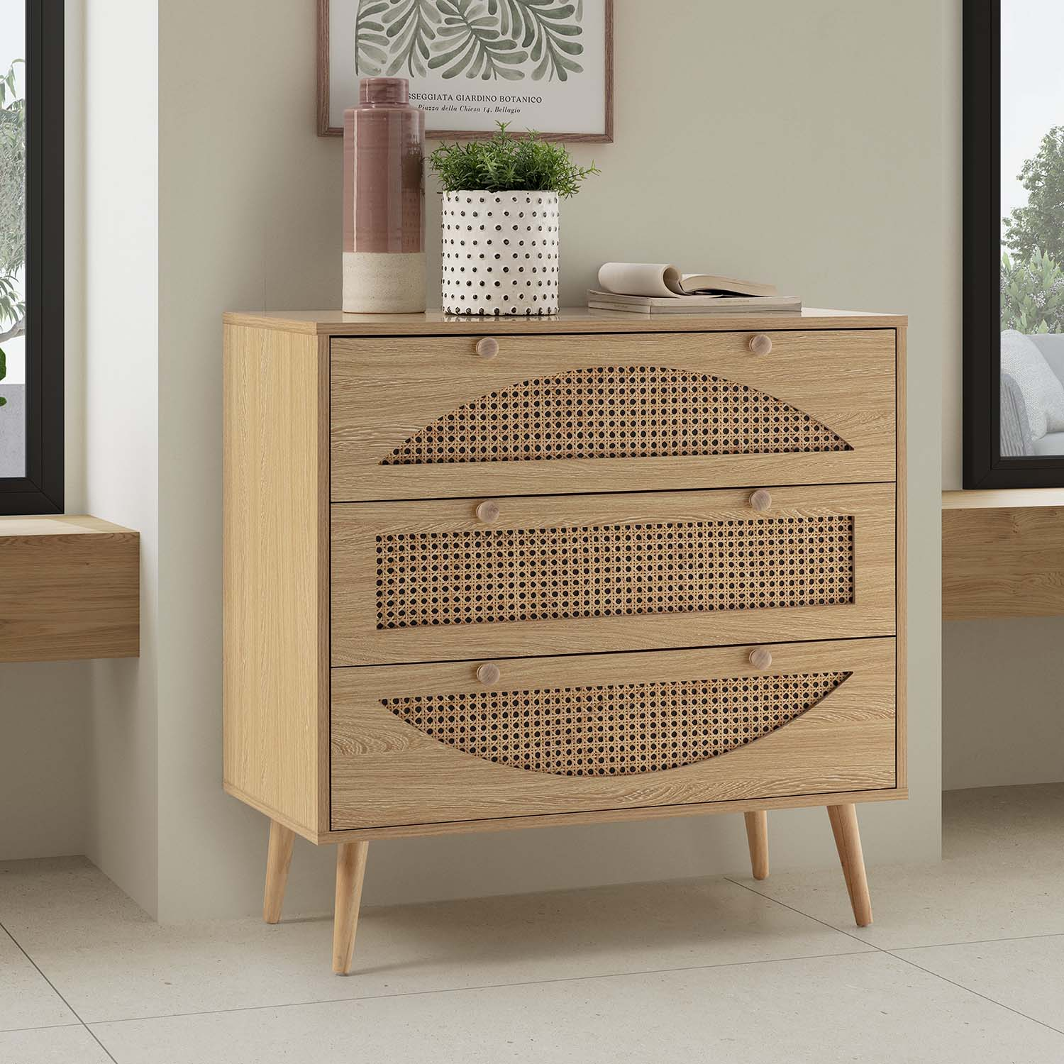 Cómoda de madera con tres cajones frontales de ratán y tiradores redondos de madera.