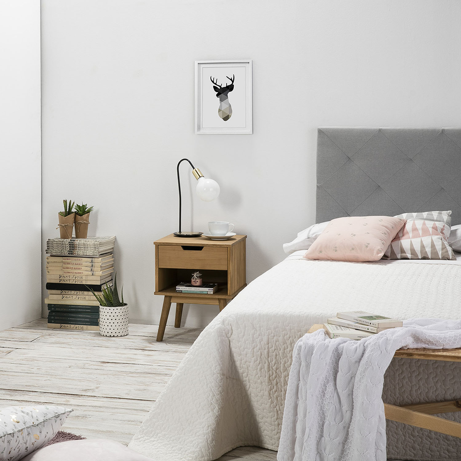 Una habitación con una cama blanca, una mesita de noche de madera y un cuadro de ciervo.