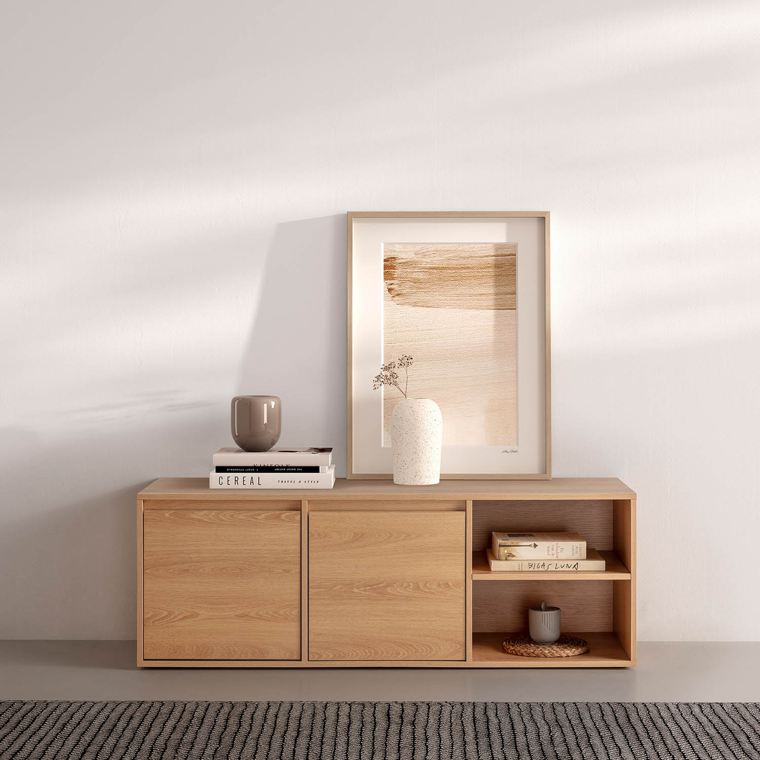 Un mueble de madera con arte, jarrones y libros. Una alfombra gris delante.