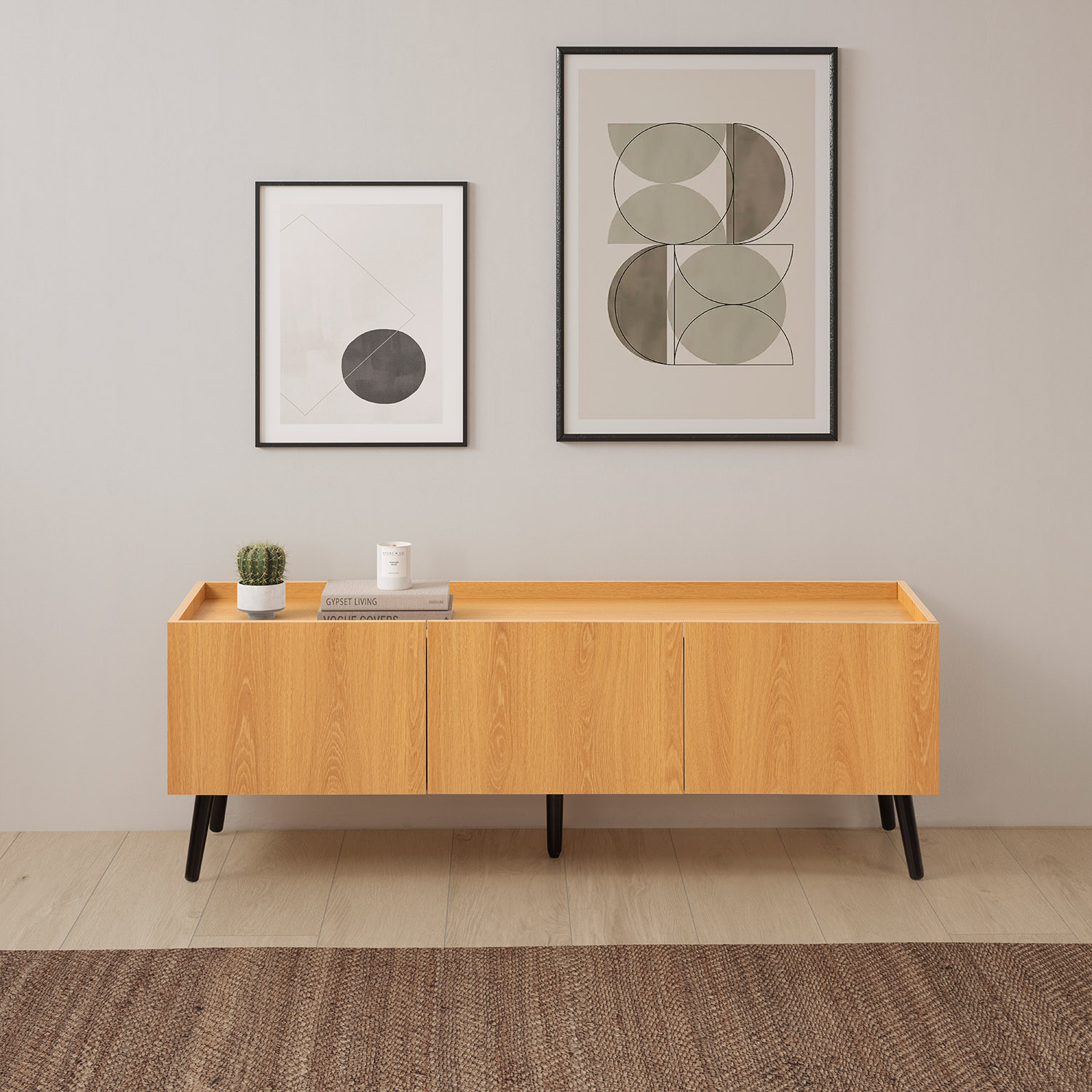 Un aparador de madera clara con tres puertas y dos cuadros enmarcados en la pared.