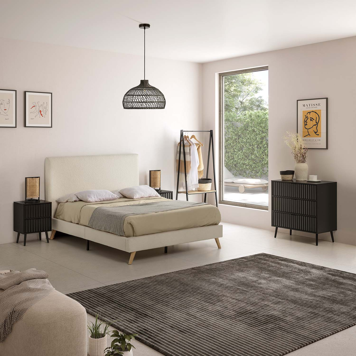 Un dormitorio con cama blanca, mesitas de noche negras y lámpara colgante de ratán.