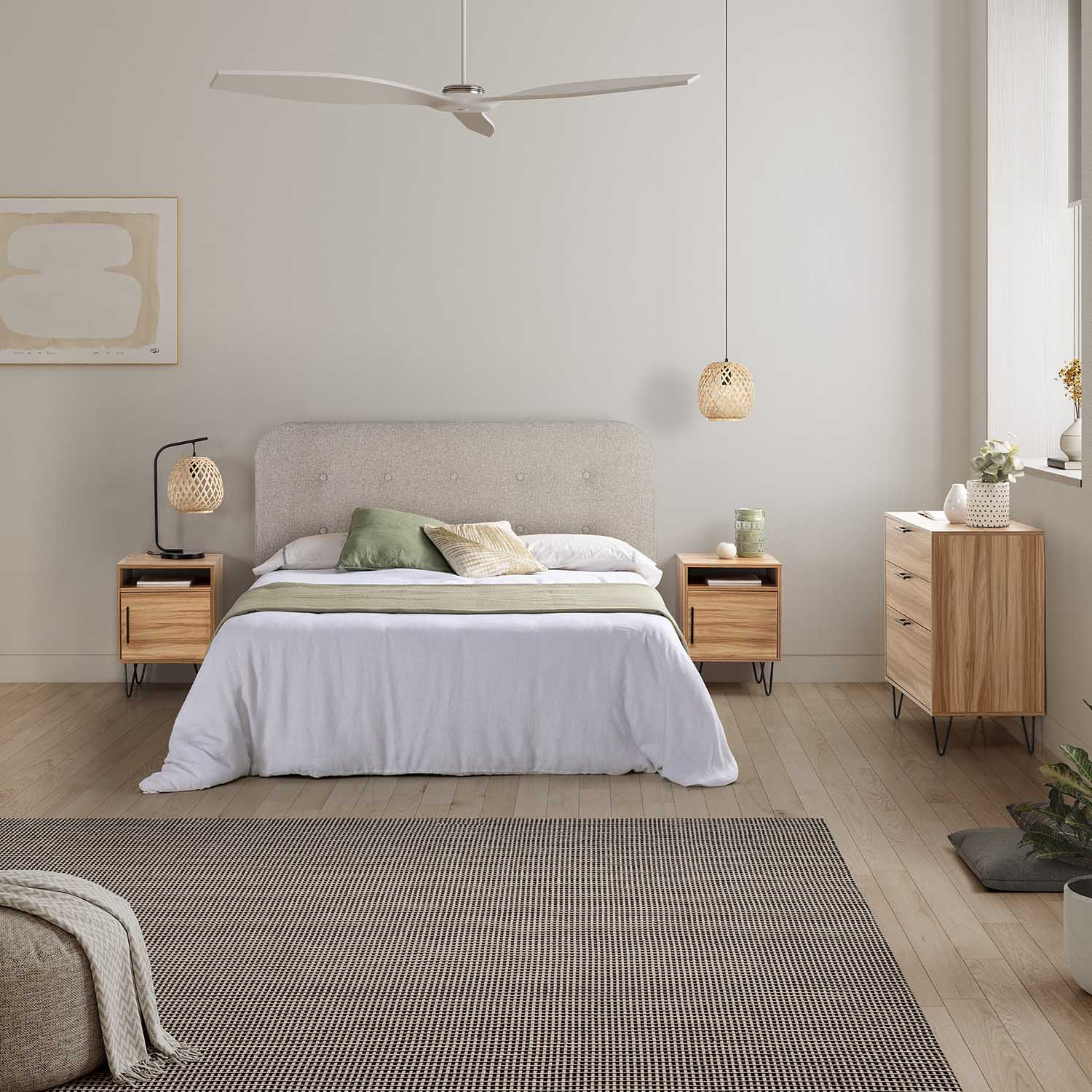 Un dormitorio luminoso con cama, mesitas de noche, cómoda y alfombra.
