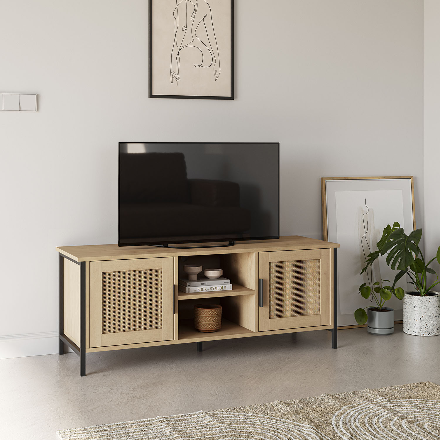 Una consola de madera con detalles de ratán debajo de un televisor y arte de pared.