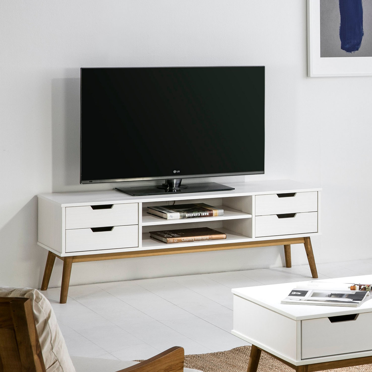 Un mueble de TV blanco moderno con patas de madera, con un televisor negro encima.