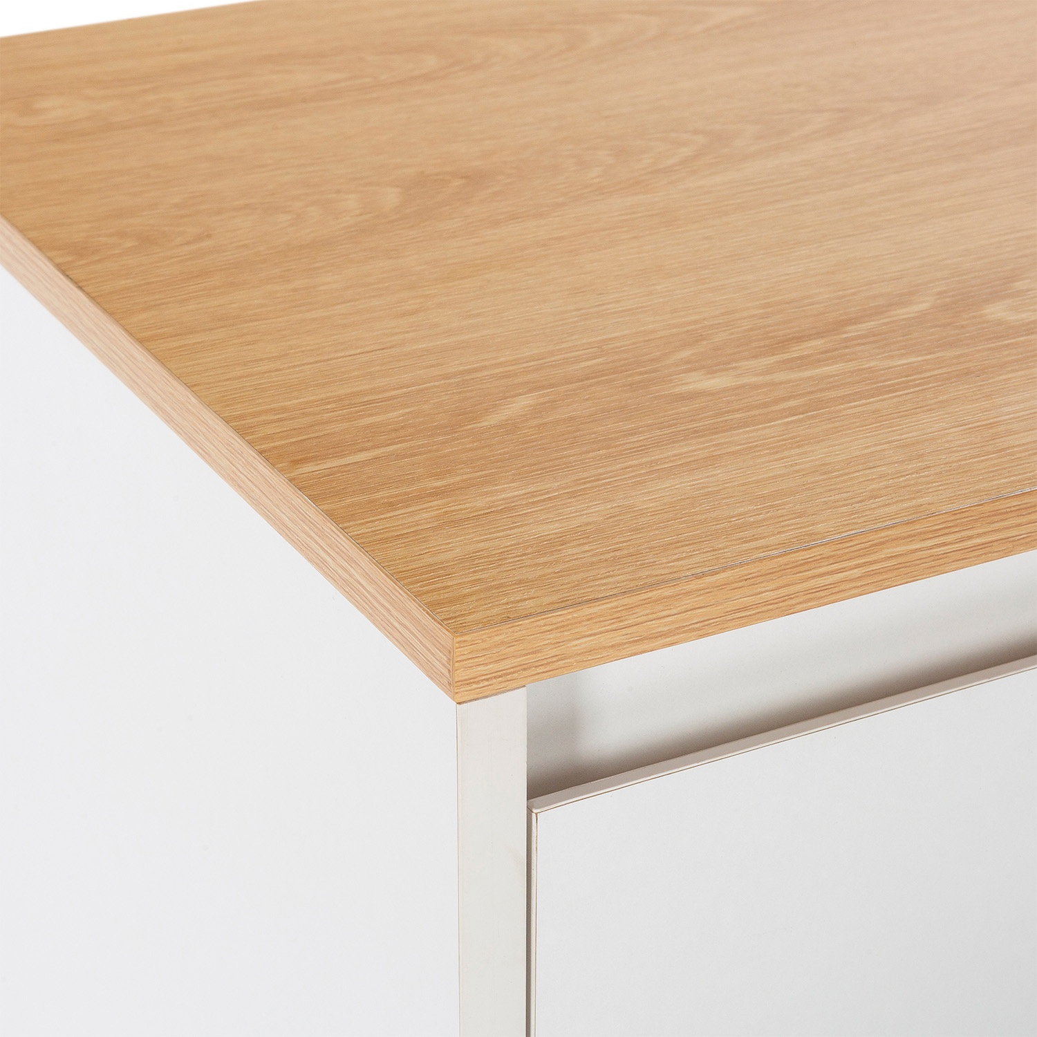 Primer plano de una mesa de madera en un mueble blanco con tirador plateado.